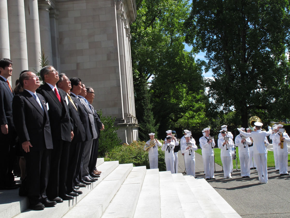Members of a Japanese delegation from Hyogo Prefecture listen to the U.S. Navy band from Naval Base Kitsap play the Japanese and U.S. national anthems on Monday in Olympia.