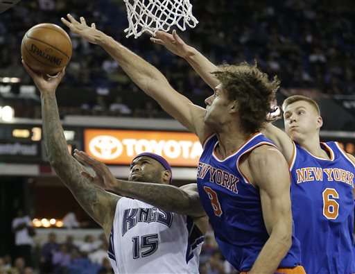 Sacramento Kings forward DeMarcus Cousins, left, goes to the basket against New York Knicks' Robin Lopez, center, and Kristaps Porzingis, right, during the second half of an NBA basketball game in Sacramento, Calif., Thursday, Dec. 10, 2015.
