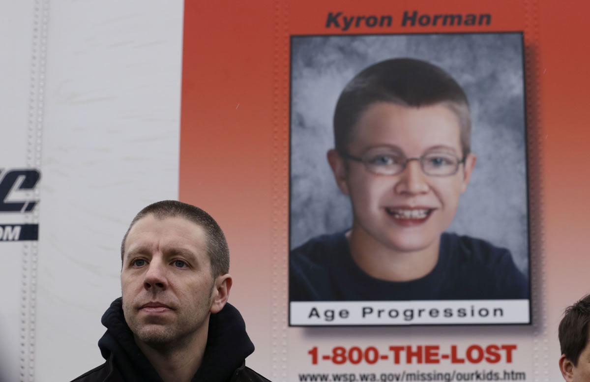Kaine Horman stands in front of an age-progressed photo posted on the side of a truck trailer of what his missing son, Kyron, could look like now during an unveiling for media Jan.