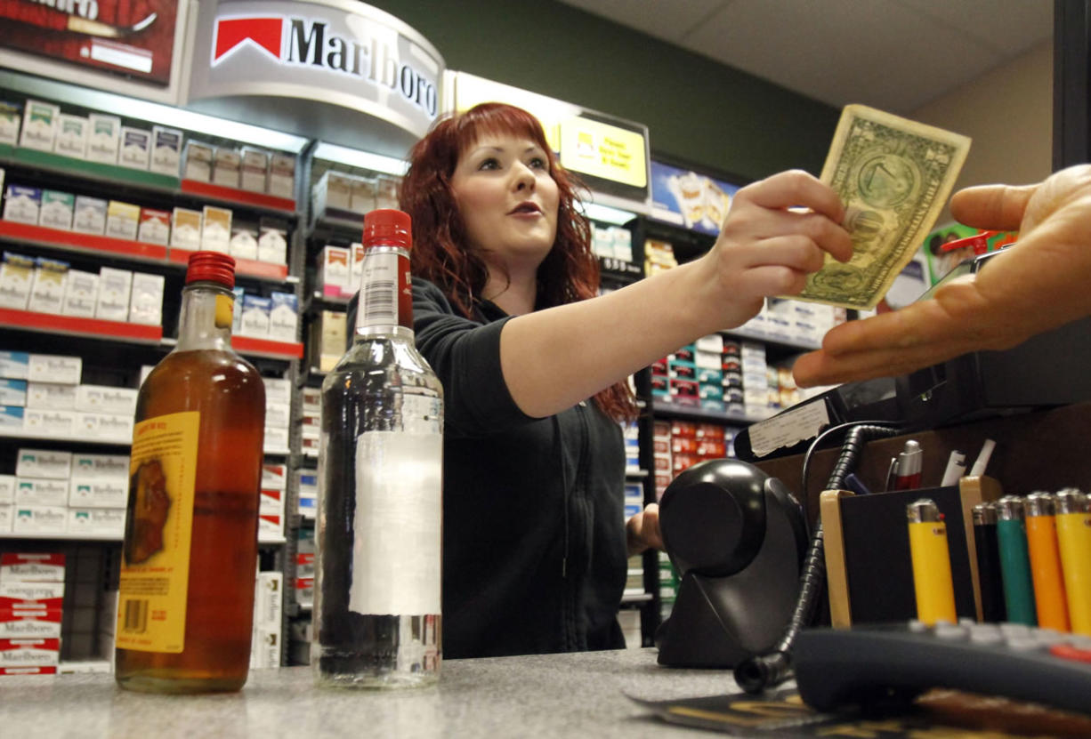 Brittany Whalen makes change for a customer at a liquor store Wednesday in north Portland, just across the Columbia River from Vancouver. New data show that Oregon liquor stores near population centers in Washington saw large increases in their sales during June, the first month that a new Washington liquor law was in place.