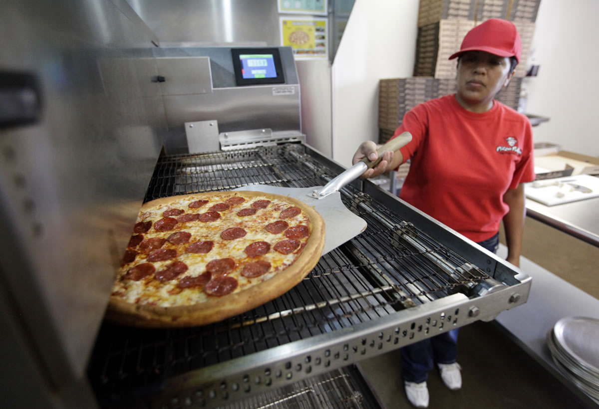 Employee Rosy Tirado pulls a pepperoni pizza from an oven at a Pizza Patron in Dallas, Texas.