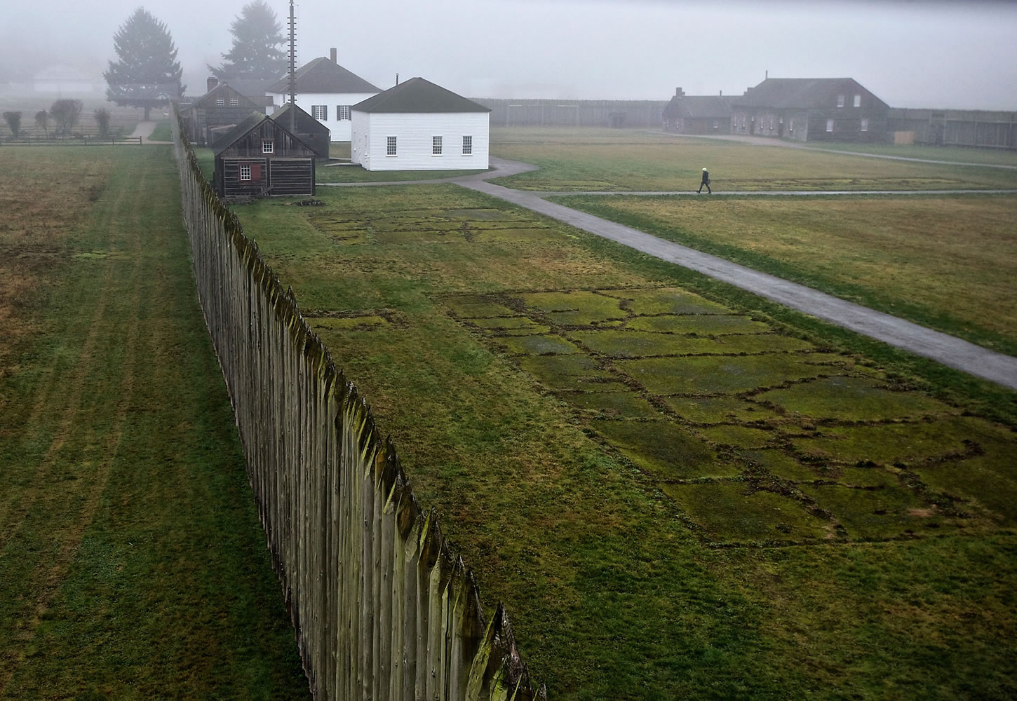 A visitor walking through Fort Vancouver National Historic Site is observed from an upper story of the bastion at the northwest corner of the reconstructed stockade.