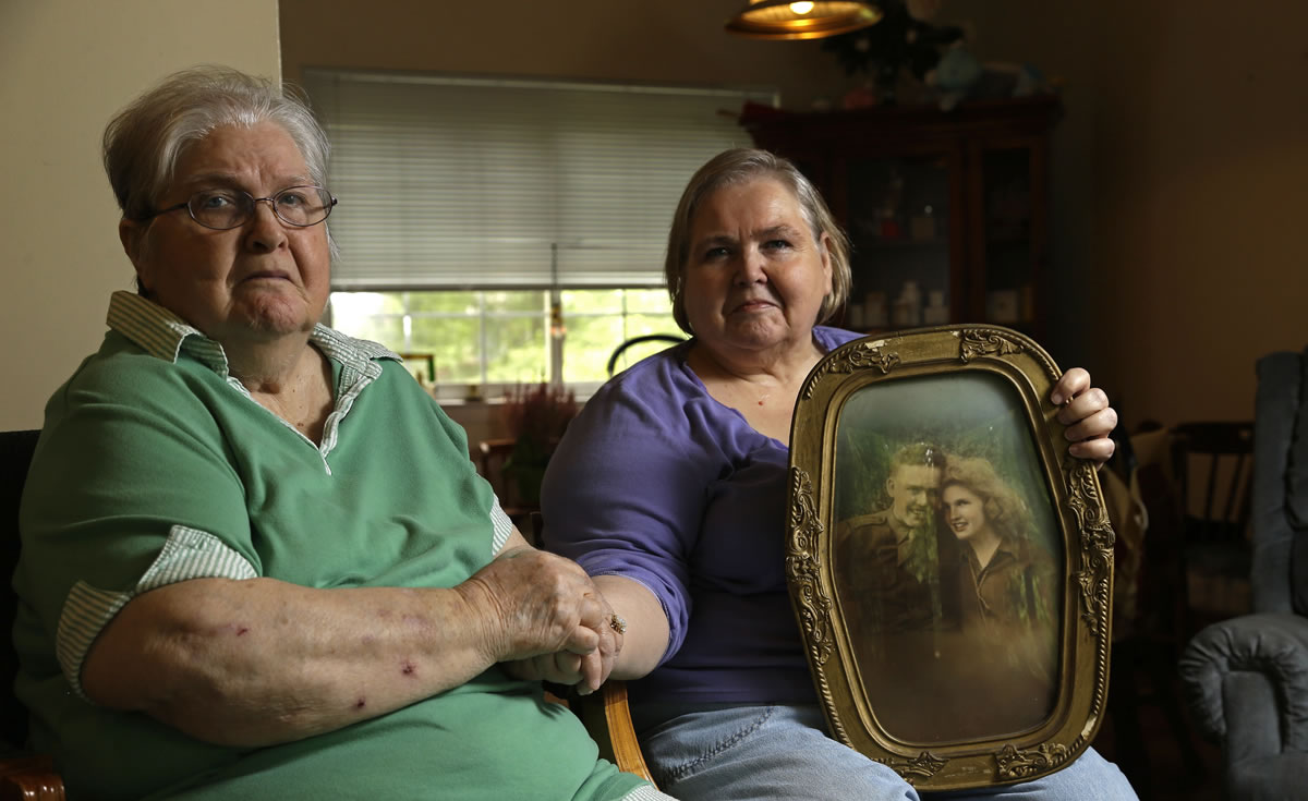 Shelia Reese, right, holds hands  July 1, in Chapel Hill, N.C., with her mother Chris Tench while holding a portrait of her parents. Her father, Kenneth F. Reese, is a soldier who is still Missing In Action from the Korean War. Tench, who was later remarried, has never known what happened to her husband.