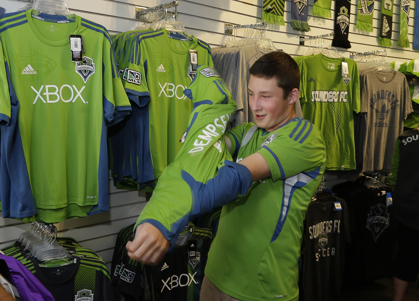 Evan Sacker, 14, of Vancouver puts on his newly-purchased Clint Dempsey No. 2 Seattle Sounders jersey Saturday in Seattle.