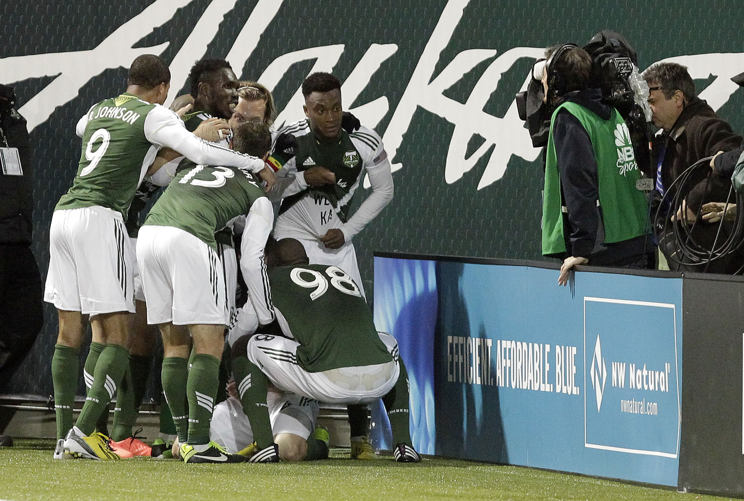 Portland Timbers players pose for the television camera at right as they celebrate scoring on Will Johnson's free kick during the second half against the San Jose Earthquake.