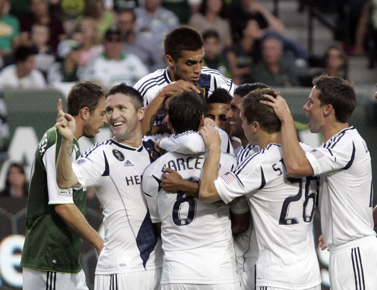 Teammates mob Los Angeles Galaxy midfielder David Beckham (not visible in middle of crowd) after he scores his second goal of the first half against the Timbers.