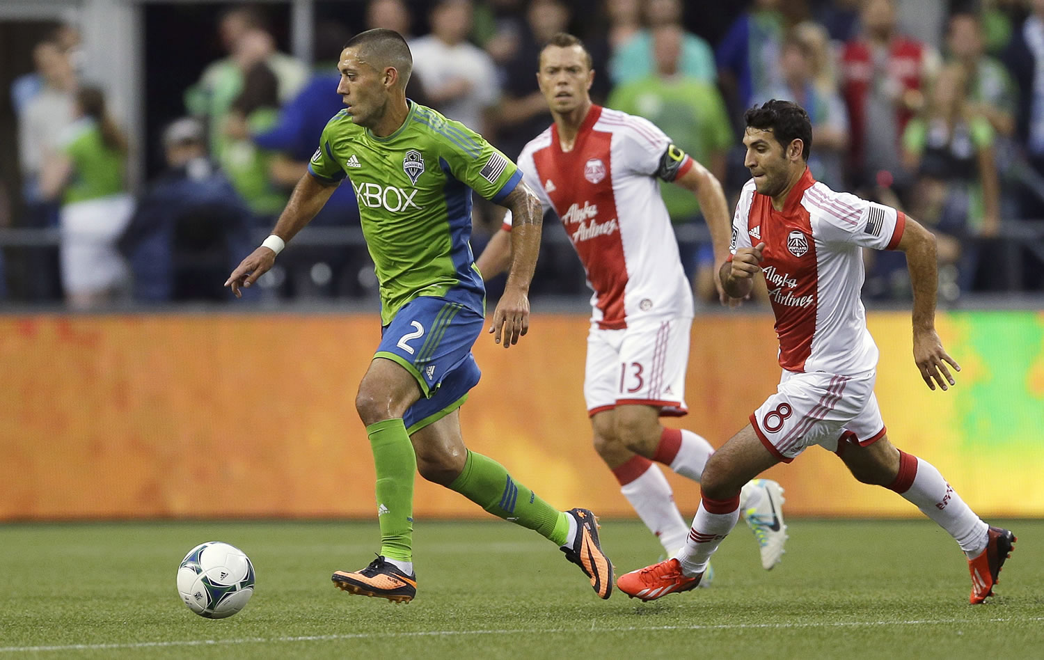 Seattle Sounders' Clint Dempsey dribbles the ball as Portland Timbers' Jack Jewsbury (13) and Diego Valeri (8) defend in the first half Sunday in Seattle.