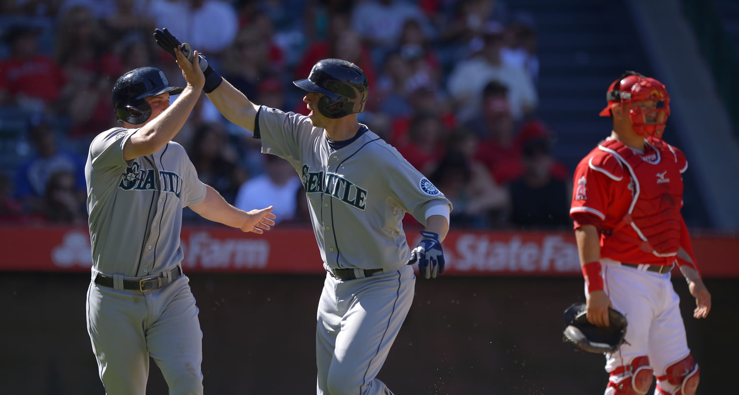 Seattle Mariners' Justin Smoak, center, is congratulated by teammate Kyle Seager after hitting a two-run home run as Los Angeles Angels catcher Hank Conger looks on during the sixth inning Sunday.