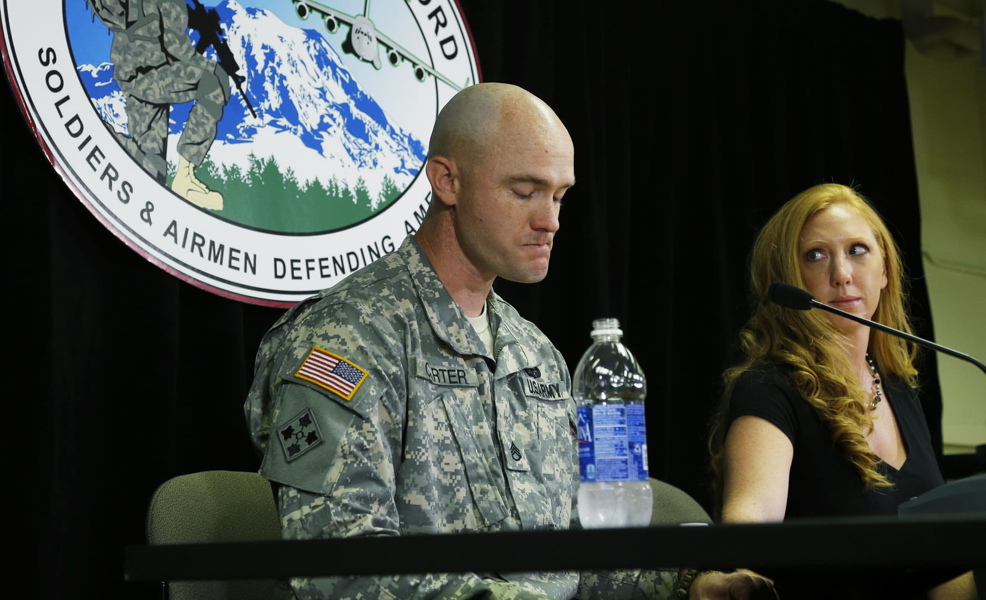 U.S. Army Staff Sgt. Ty Carter, left, becomes emotional as he talks to reporters Monday at Joint Base Lewis-McChord in Washington as his wife, Shannon Carter, looks on at right. Ty Carter will be awarded the Medal of Honor in August for his actions during a 2009 battle at a mountain outpost in Afghanistan where U.S.