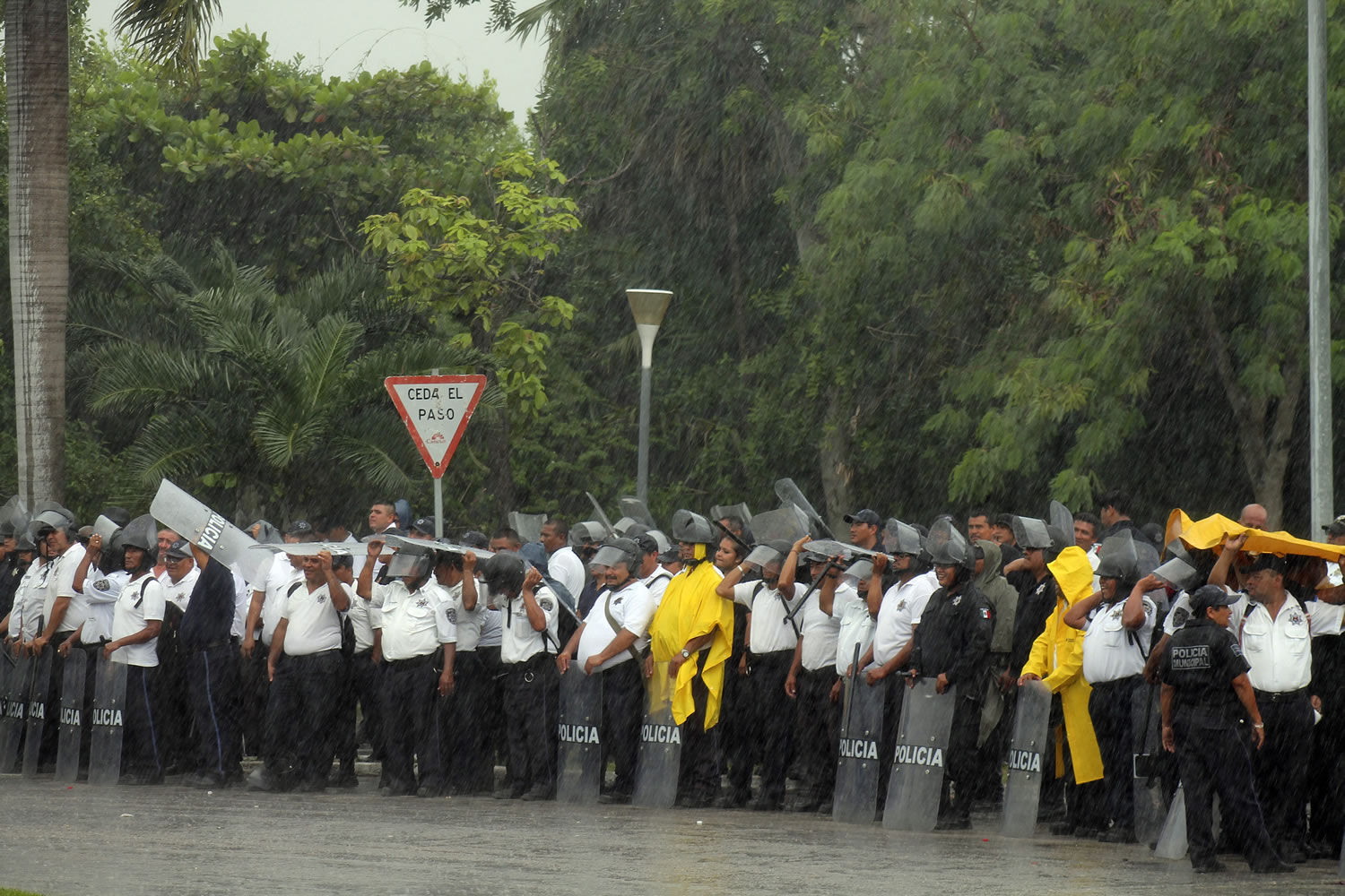 Riot police guarding the entrance of the hotel from protesting teachers stand under heavy rains in the Caribbean resort city of Cancun, Mexico, on Tuesday.