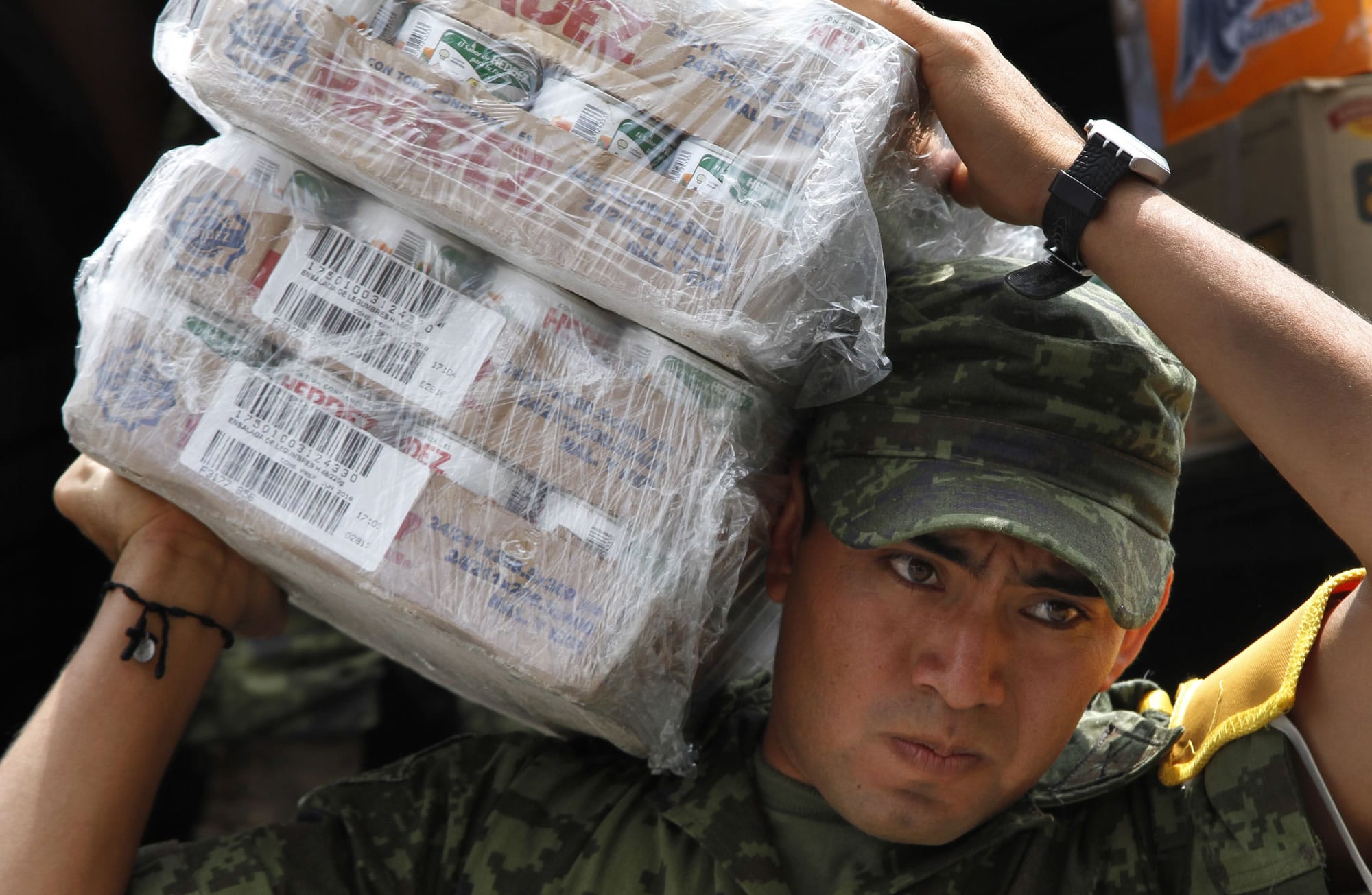 A soldier carries cartons of canned vegeatables Friday as part of the humanitarian aid bound for storm victims of Tropical Storm Manuel, in Mexico City.