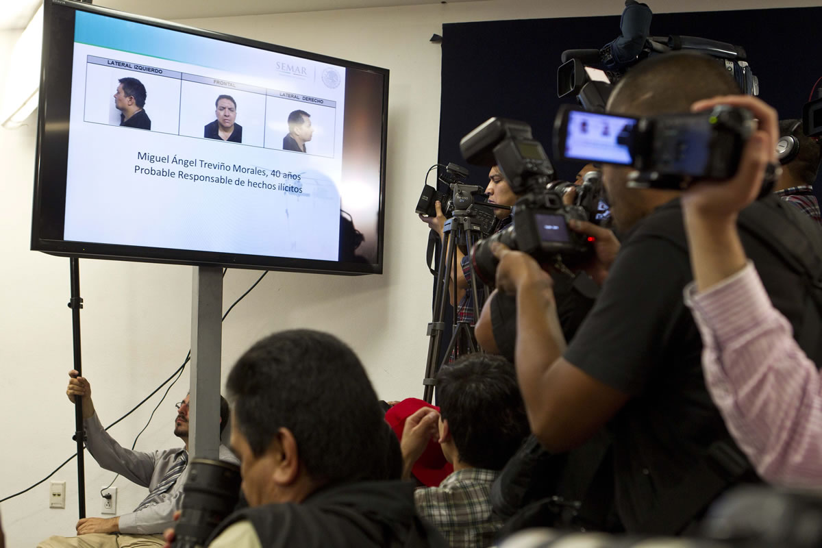 Reporters take videos and photos of mug shots showed on a TV screen of the Zetas drug cartel leader Miguel Angel Trevino Morales during a news conference given by the Mexican government in Mexico City on Monday.