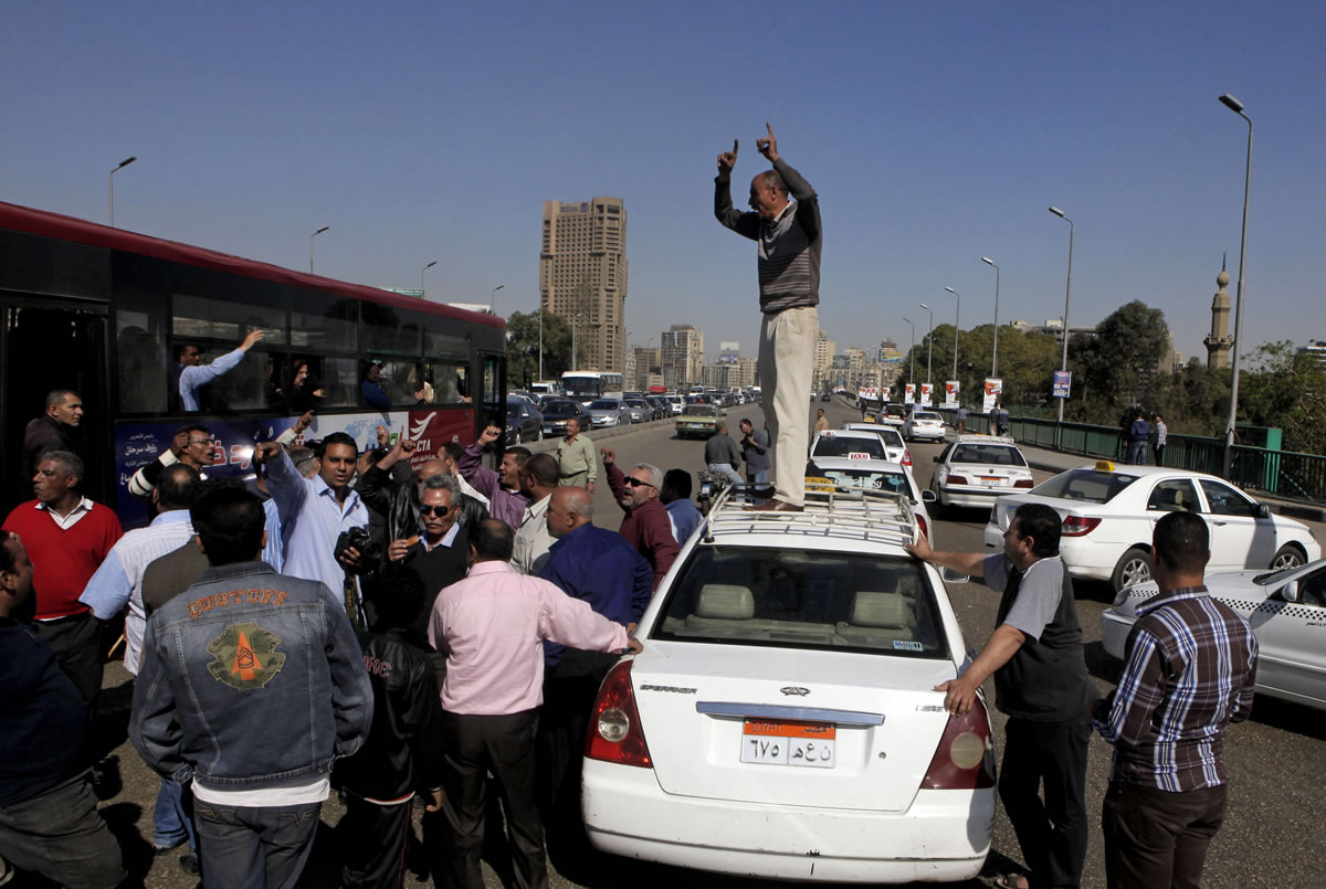 An Egyptian taxi driver stands on his car as he and others block part of the 6th October bridge in central Cairo, Egypt, on Monday.