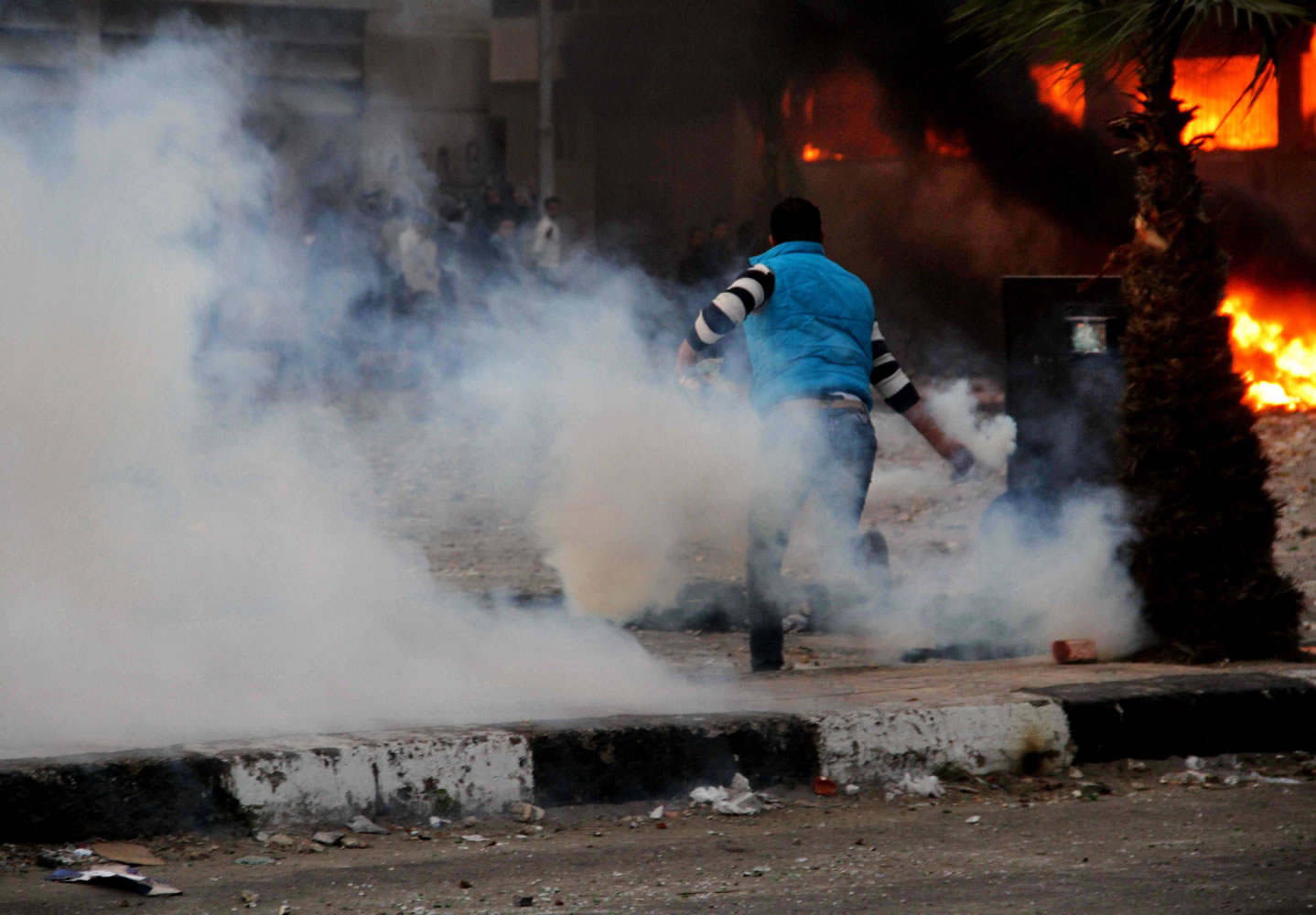 An Egyptian protester throws back a tear gas canister toward police, unseen, during clashes in Port Said, Egypt, on Monday.