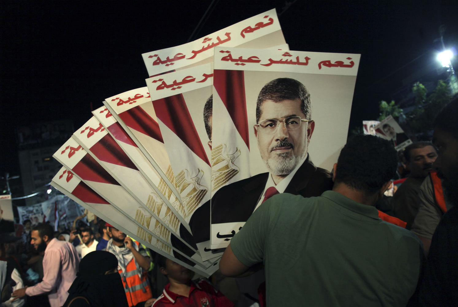 A supporter of Egypt's ousted President Mohammed Morsi holds posters with Arabic writing which reads &quot; Yes for legality,&quot; during a protest outside Rabaah al-Adawiya mosque, where protesters have installed a camp and hold daily rallies at Nasr City in Cairo, Egypt, on Tuesday.