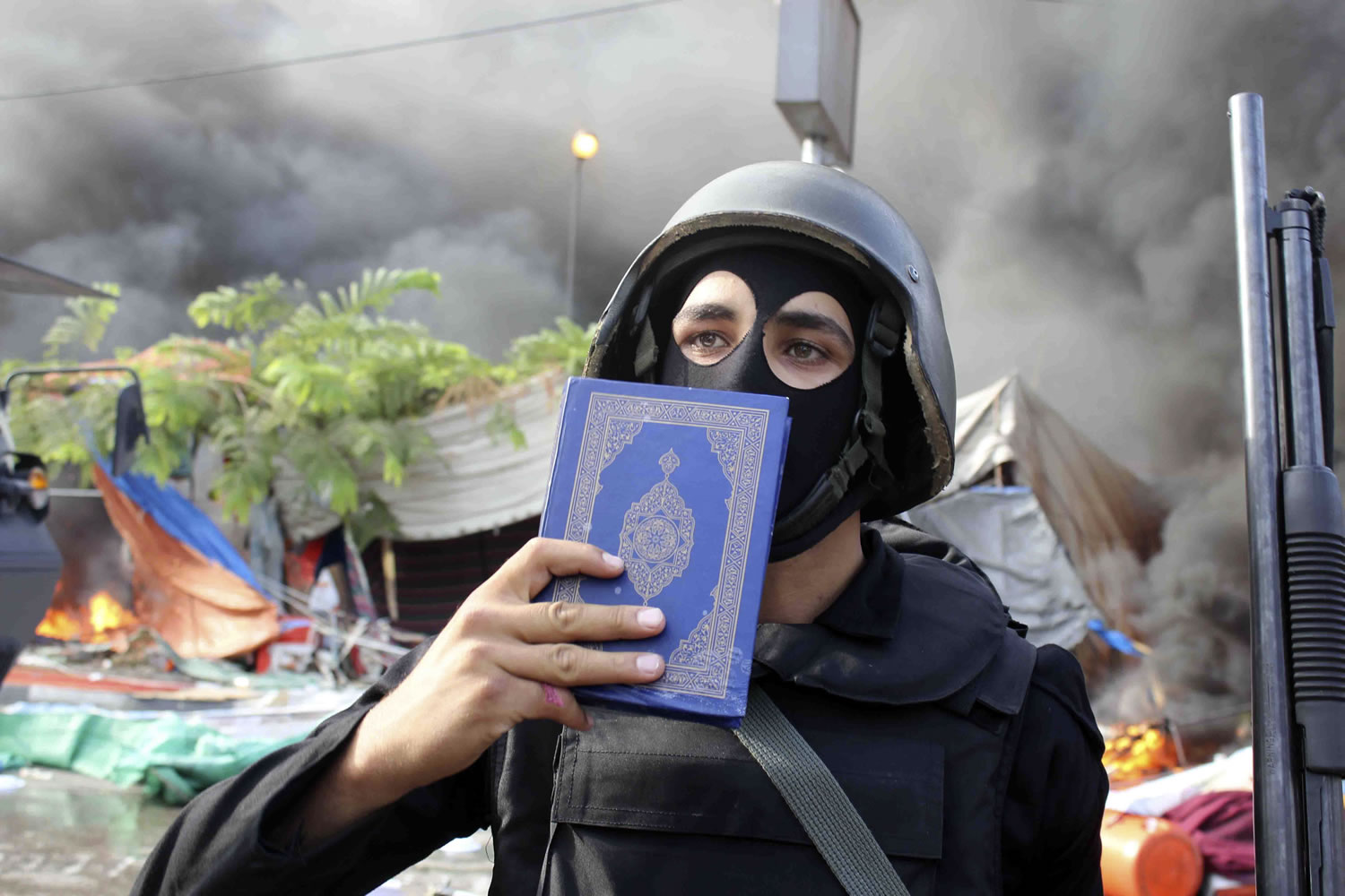 A member of the Egyptian security forces holds up a copy of the Quran as they clear the smaller of the two sit-ins by supporters of ousted Islamist President Mohammed Morsi, near the Cairo University campus in Giza, Cairo, Egypt, on Wednesday.