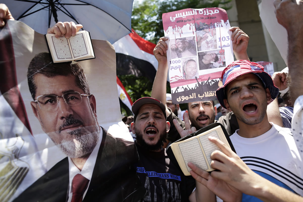 Supporters of ousted Egyptian President Mohmmed Morsi hold Islam's holy book, the Quran, as they chant slogans against Egyptian Defense Minister Gen.