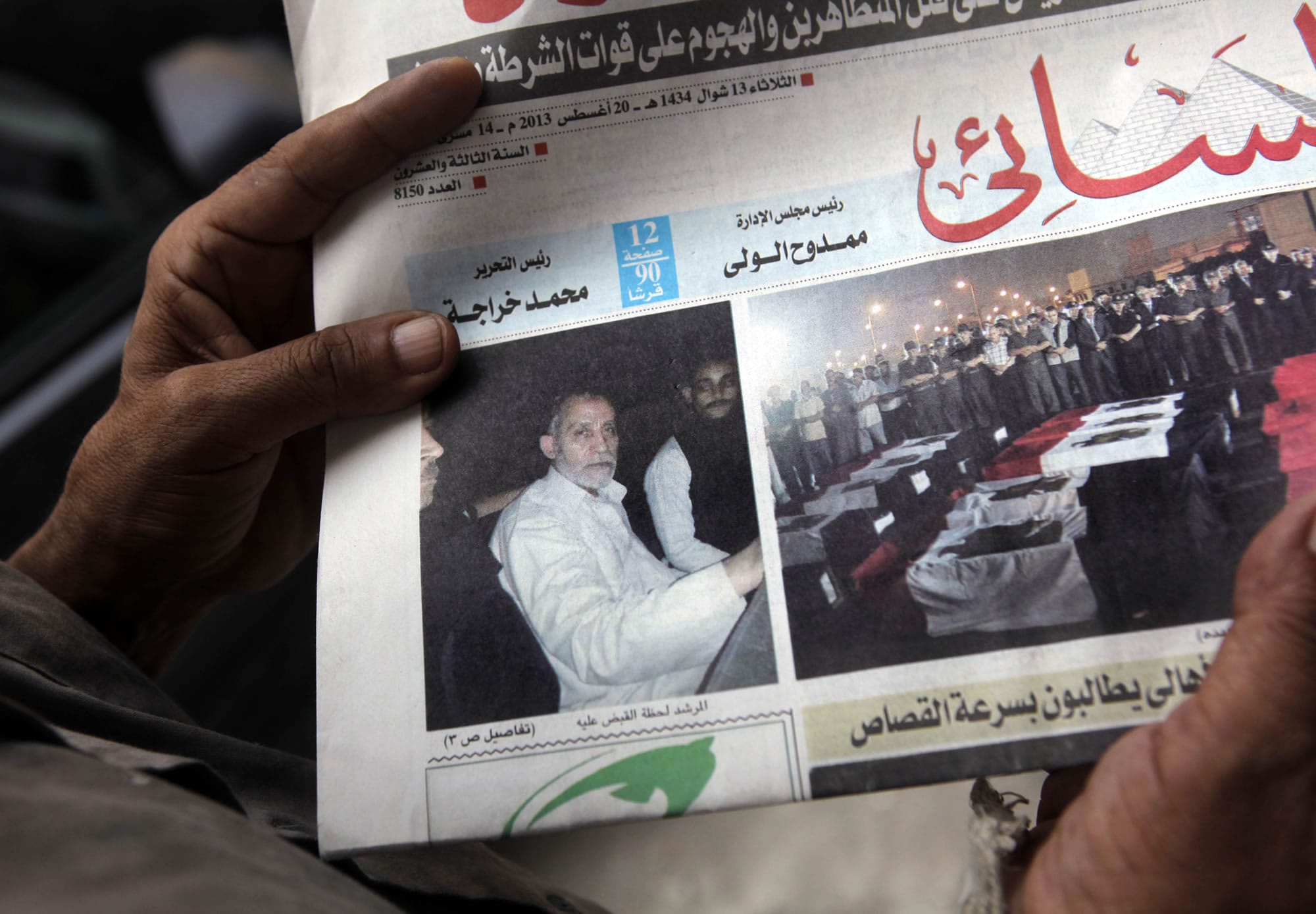 An Egyptian holds Al-Ahram newspaper in Cairo, Egypt, on Tuesday fronted by a picture of Mohammed Badie, the supreme leader of the Muslim Brotherhood, left, and pictures of flag-draped coffins containing the bodies of slain off-duty policemen in North Sinai.