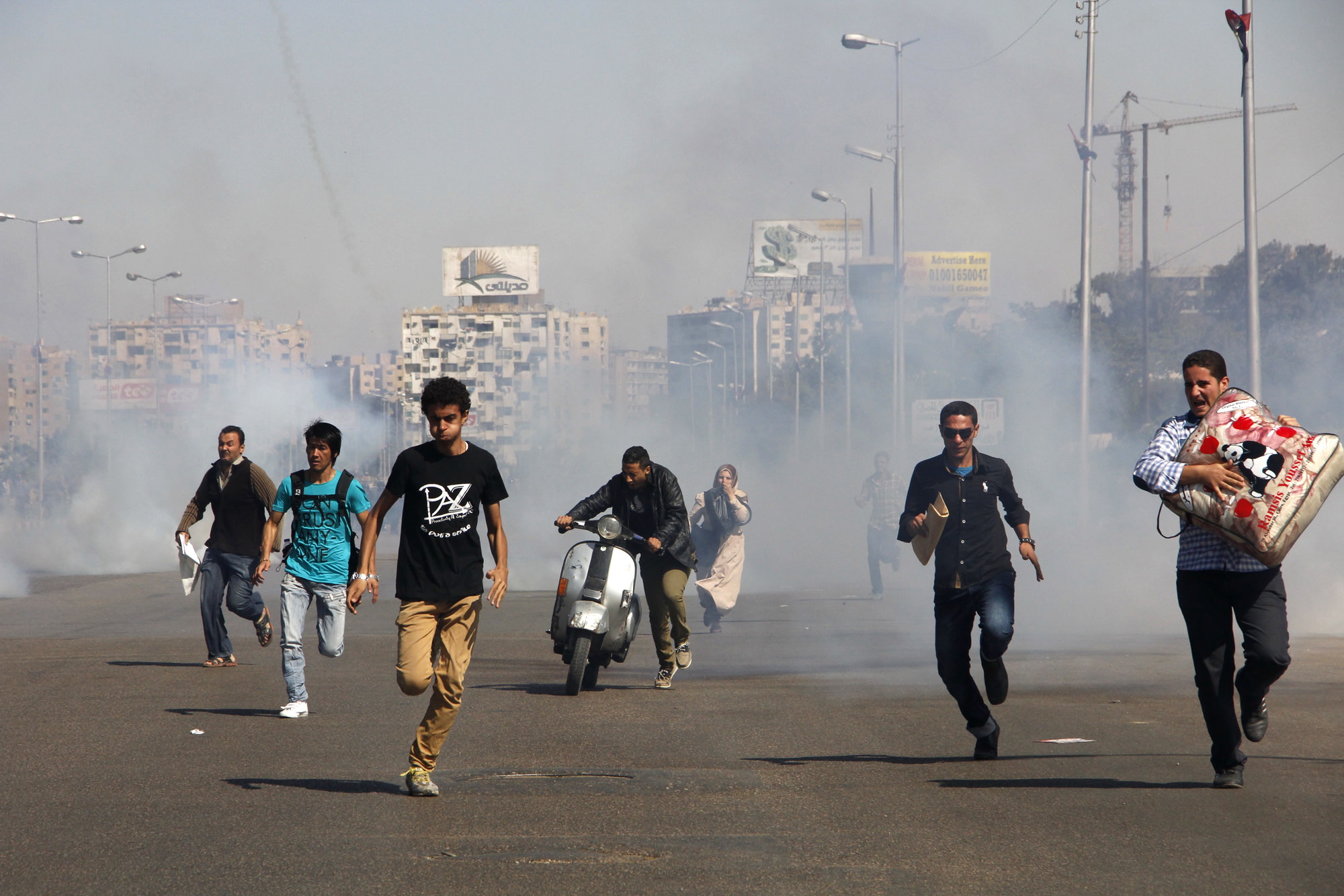 Egyptians run from tear gas after clashes erupted between Al-Azhar students and police forces during a protest Sunday in the Nasr City district of Cairo. The protests were the second in two days at Al-Azhar University, Sunni Islamis most prominent center of learning. Many supporters of ousted Egyptian President Mohammed Morsi's Muslim Brotherhood group are students at Al-Azhar, a stronghold of the group and steps from former site of an Islamists' sprawling protest camp which came under heavy crackdown by security forces on Aug.