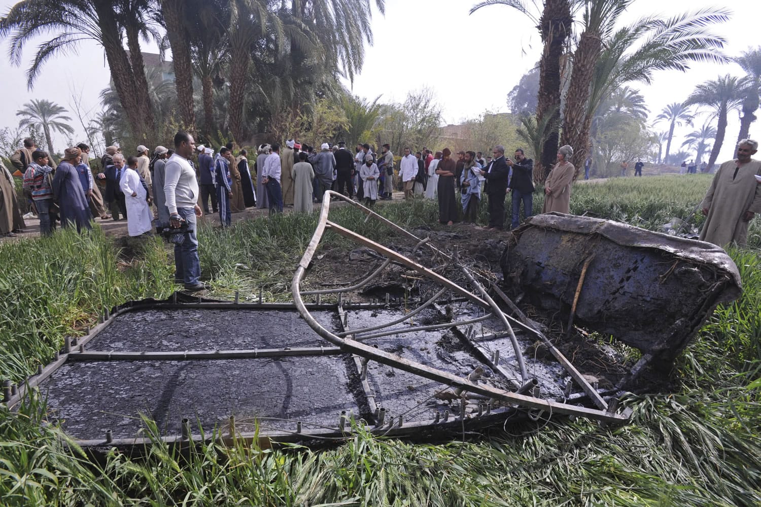 Egyptians gather at the site of a balloon crash where the remains of the burned gondola are seen, outside al-Dhabaa village, just west of the city of Luxor, south of Cairo, Egypt, on Tuesday.
