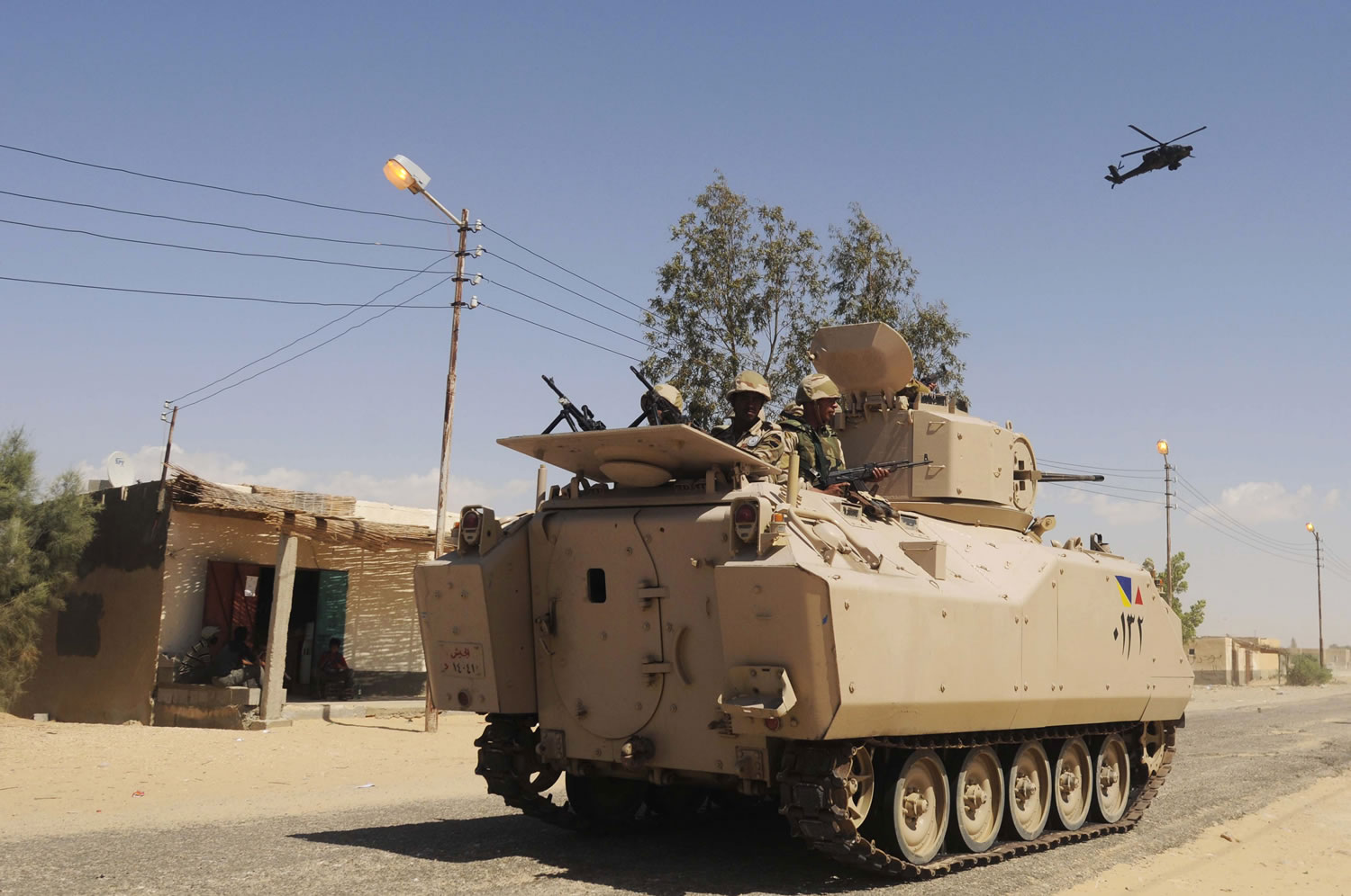 Egyptian Army soldiers patrol in an armored vehicle backed by a helicopter gunship during a May sweep through villages in Sheikh Zuweyid, northern Sinai, Egypt.