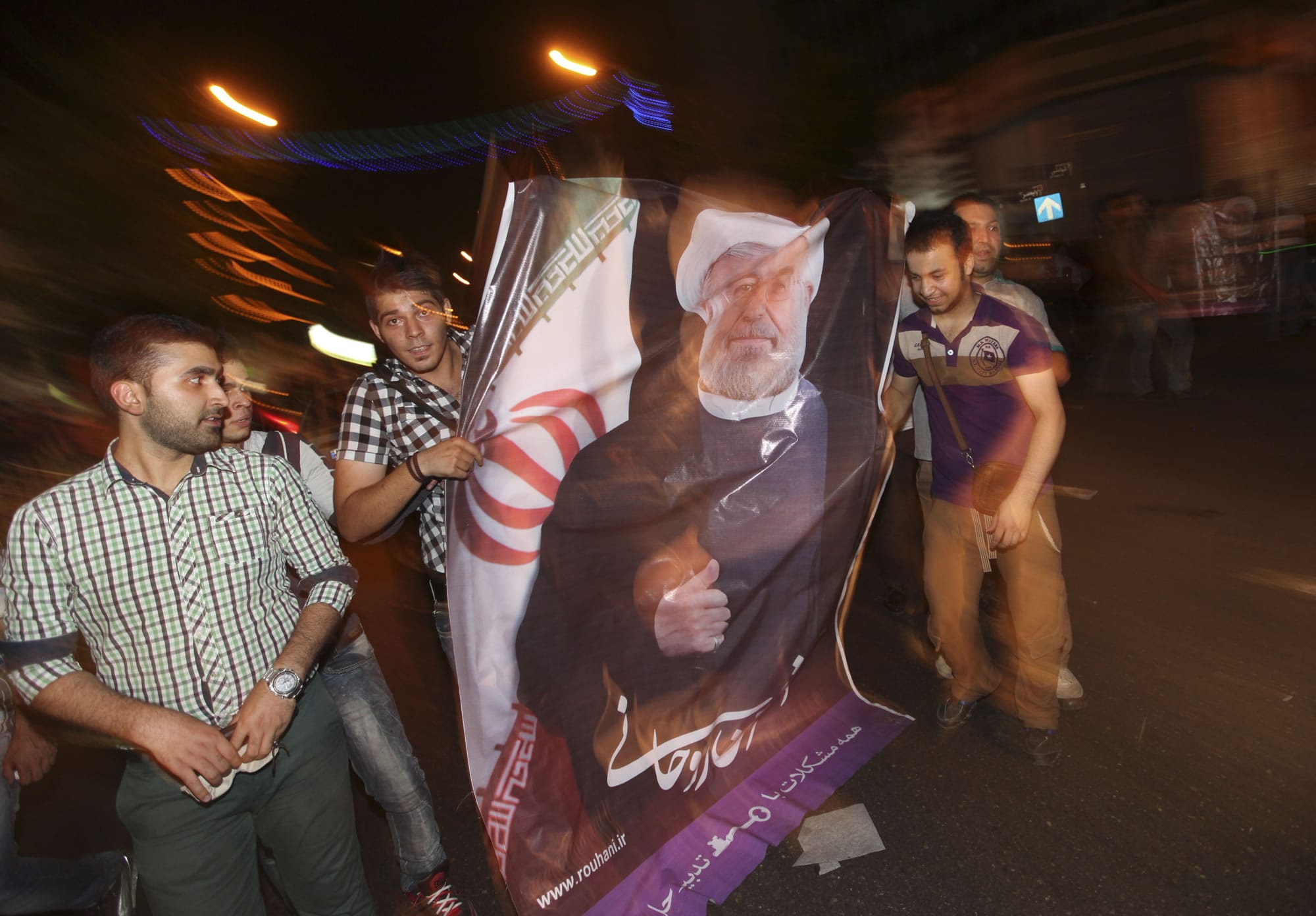 Supporters of the winning Iranian presidential candidate Hasan Rowhani, carry a banner depicting him, at a celebration gathering  in Tehran, Iran, on Saturday.
