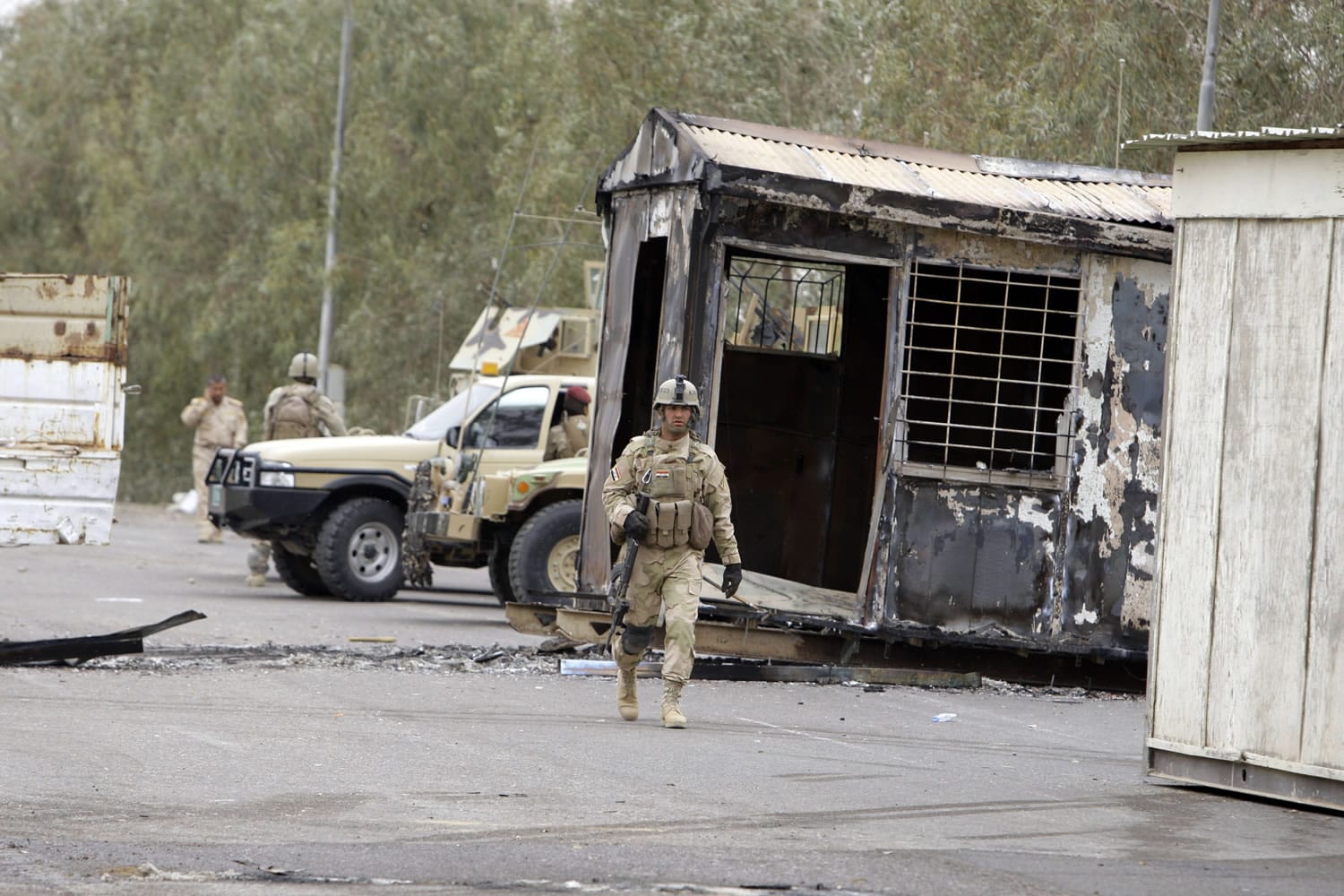 Associated Press files
Iraqi Army soldiers stand guard near burned trailers at Camp Ashraf north of Baghdad, Iraq, in April 2011. More than 50 members of an Iranian dissident group were killed inside the camp Sunday.