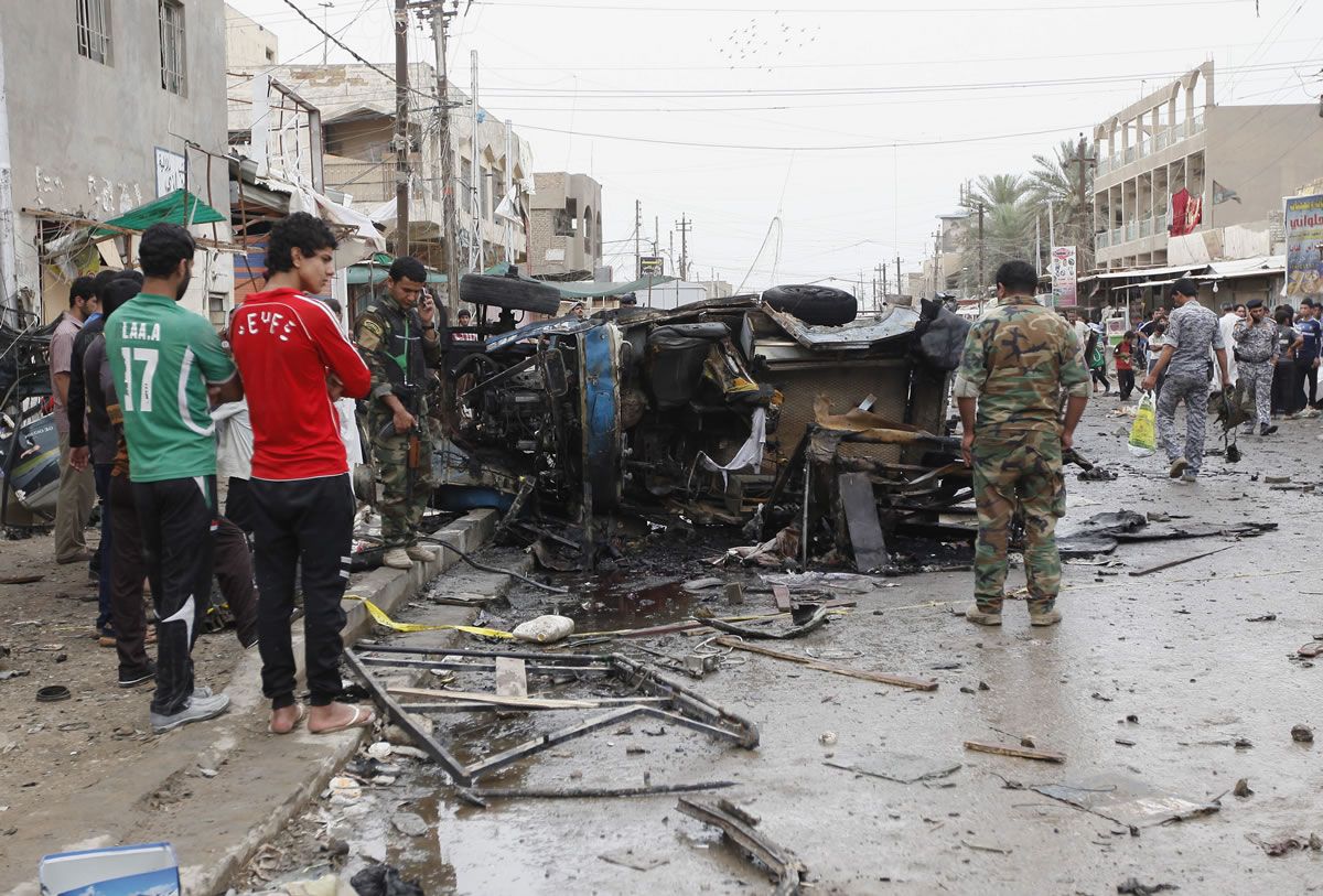 Iraqi security forces members and civilians gather at the scene of a car bomb attack in Kamaliyah neighborhood, a predominantly Shiite area of eastern Baghdad, Iraq, on Monday.