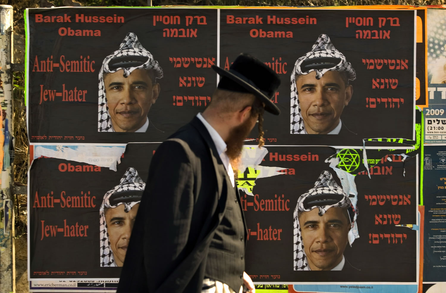 An Ultra-Orthodox Jewish man walks past posters depicting U.S.