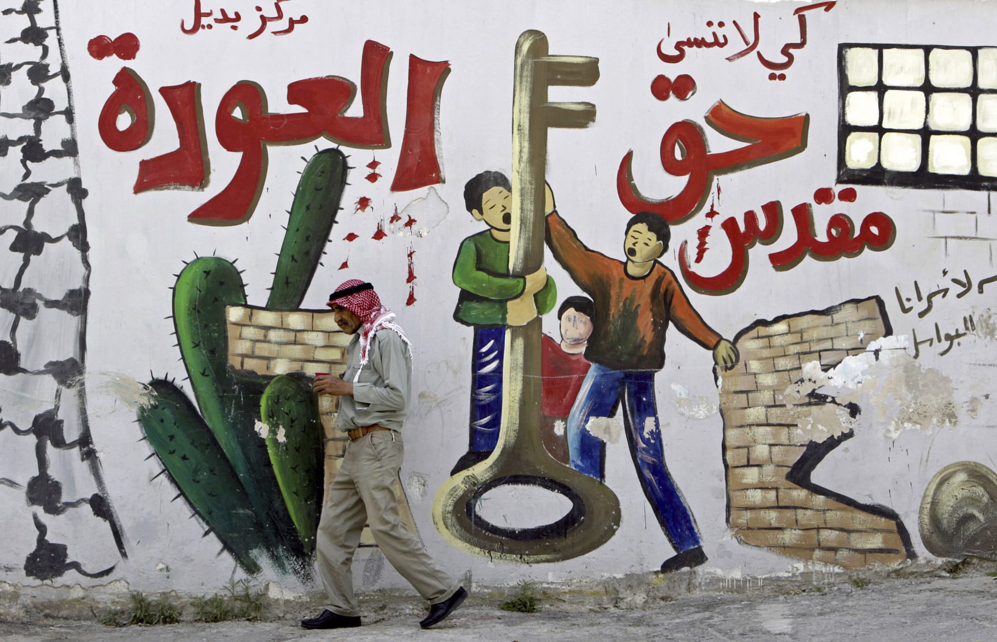 Palestinian refugee Mahmoud Al-Amer, 78, walks past a mural in the West Bank refugee camp of Jenin on Monday.
