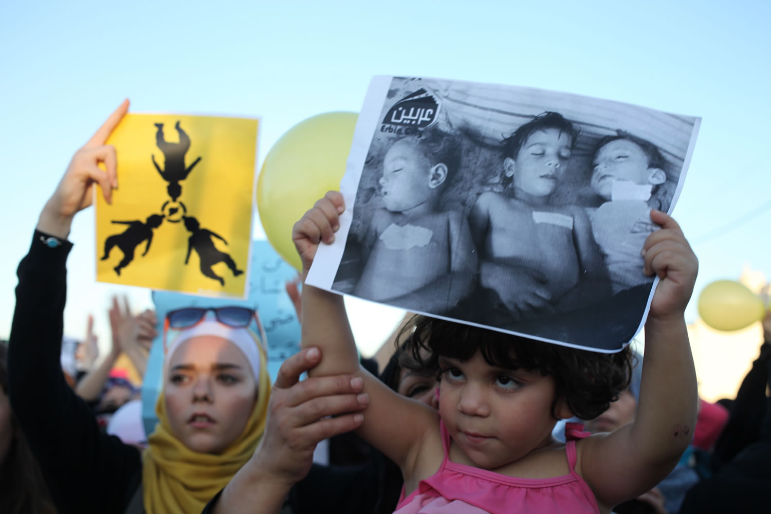 Syrian protesters carry placards showing dead Syrian children, during a protest in front of the Syrian embassy to condemn the alleged poison gas attack on the suburbs of Damascus during a protest in front of the Syrian embassy,  in Amman, Jordan, on Friday.