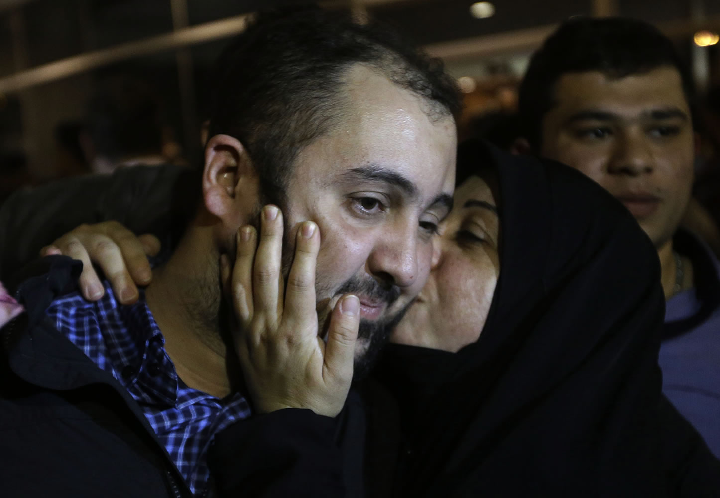One of the nine released Lebanese Shiite pilgrims who were kidnapped by a rebel faction in northern Syria in May 2012, left, is kissed by his wife, right, upon his arrival at Rafik Hariri international airport, in Beirut, Lebanon, Saturday, Oct. 19, 2013.