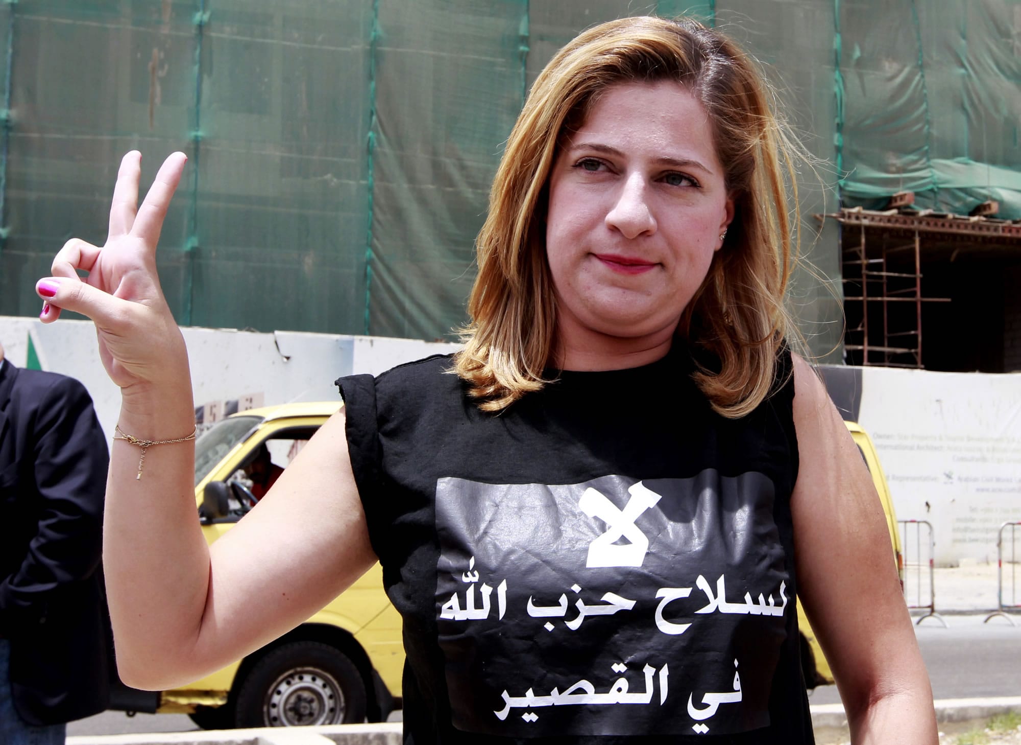 A Lebanese activist wearing a shirt with Arabic that reads, &quot;No to Hezbollah weapons in Qusair,&quot; flashes the victory sign Sunday during a protest against the participation of Hezbollah in the Syrian war at Martyrs square in Beirut.