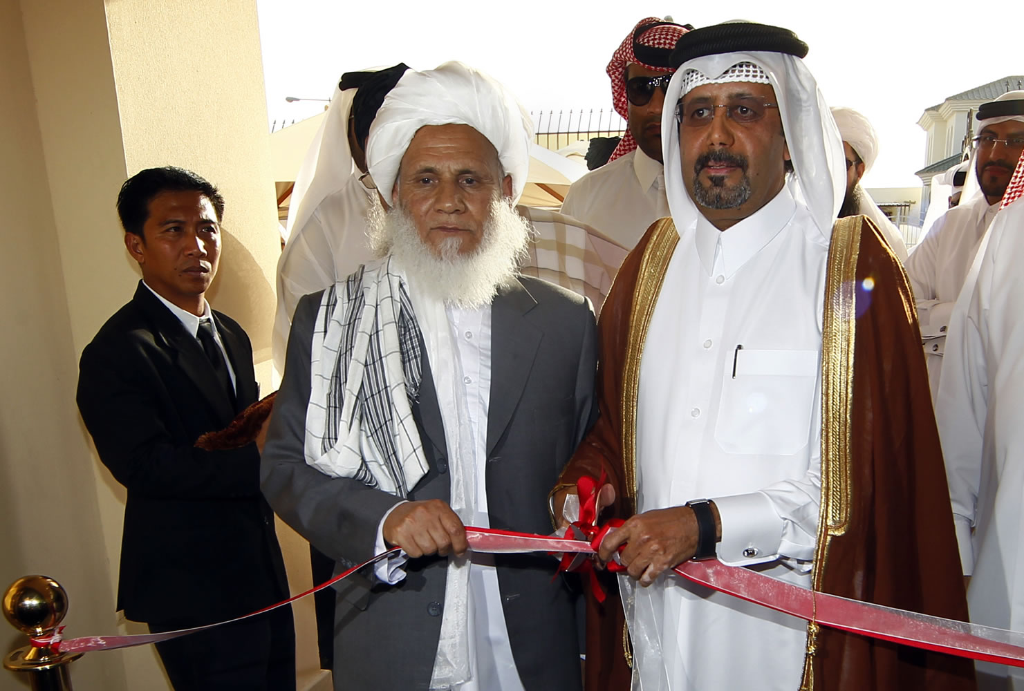 Qatari Assistant Minister for Foreign Affairs Ali bin Fahd al-Hajri, center right, and Jan Mohammad Madani, center left, a Taliban official, cut the ribbon at the official opening ceremony of a Taliban office Tuesday in Doha, Qatar.