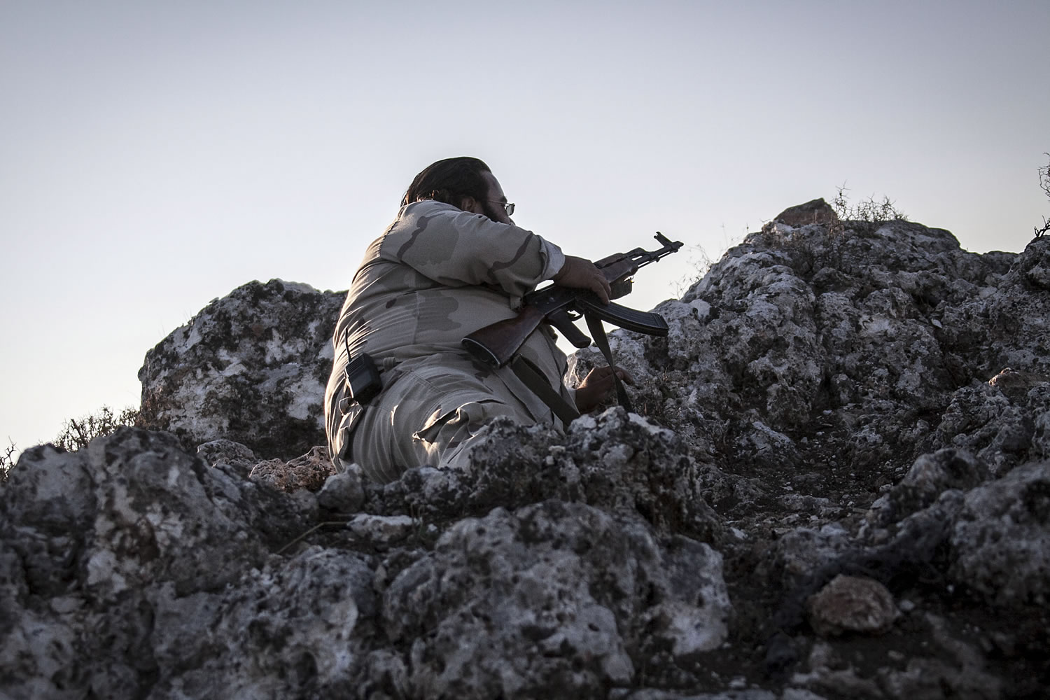 A Syrian opposition fighter takes cover during exchange of fire with government forces in Telata village, a frontline located at the top of a mountain in the Idlib province, northwest countryside of Syria on Sunday.