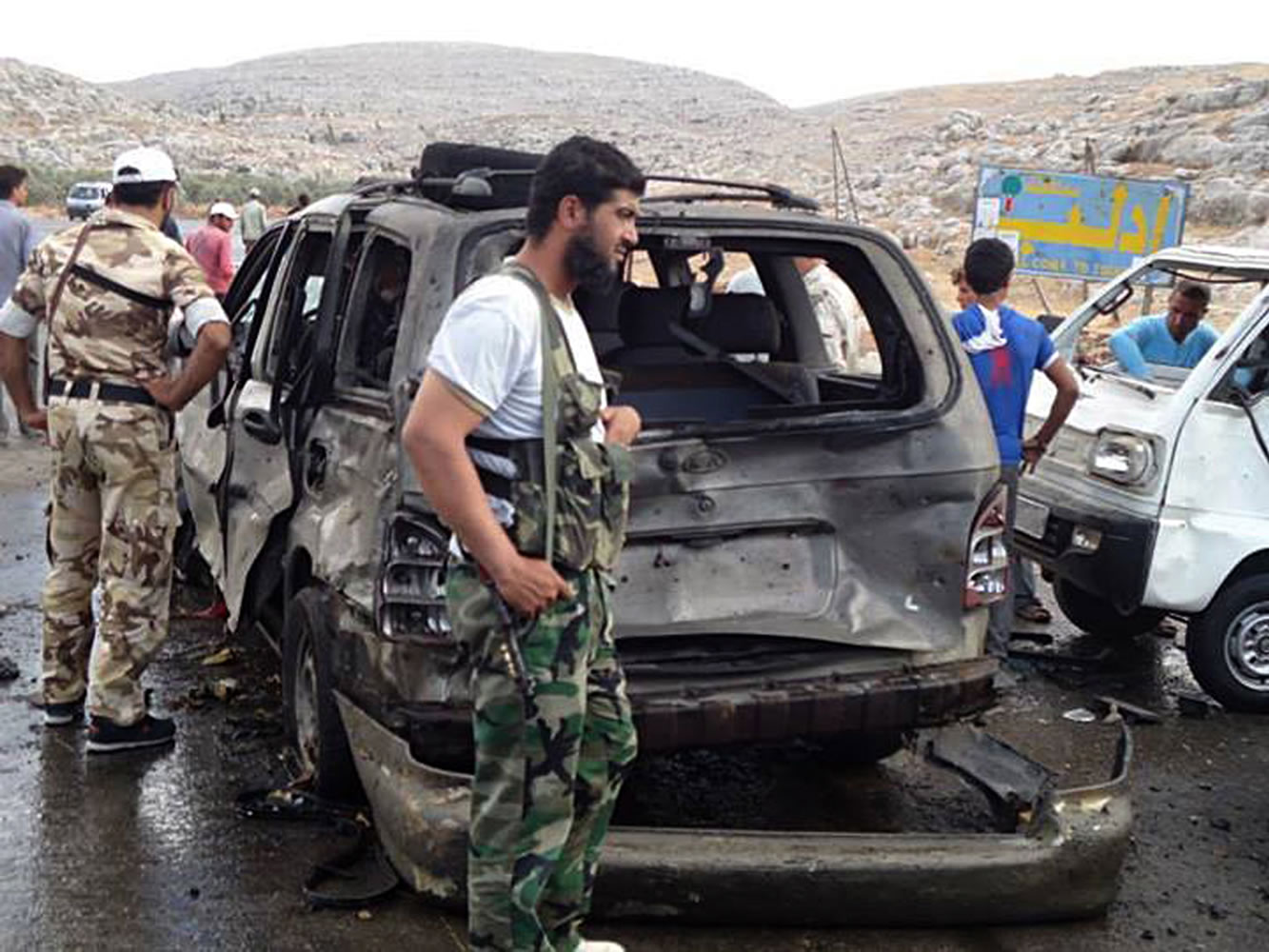 Syrian rebels with damaged cars at the scene where a car bomb exploded at a crossing point along Syria's volatile border with Turkey, in Bab al-Hawa, Syria, on Tuesday.