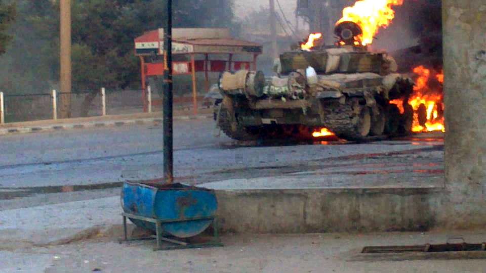 In this citizen journalism image provided by The Syrian Revolution against Bashar Assad, a Syrian military tank caught on fire during clashes with Free Syrian army fighters in Joubar a suburb of Damascus, Syria, on Wednesday.