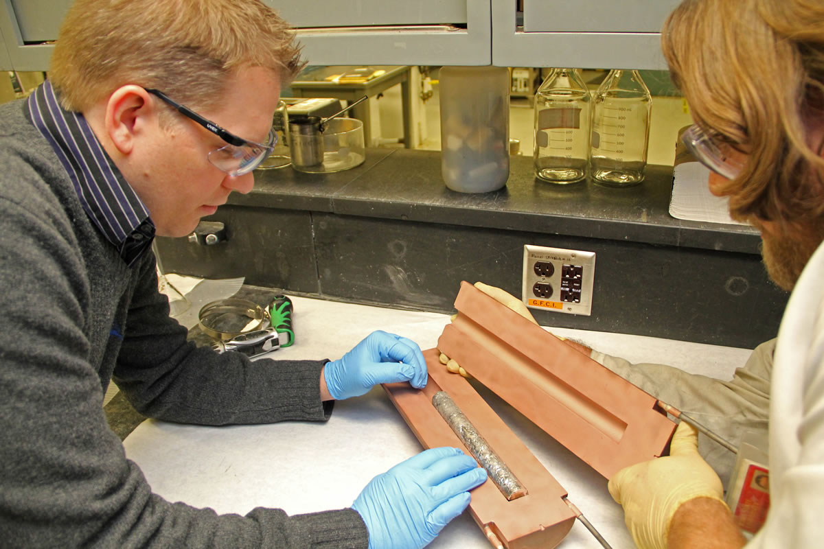 Ames Laboratory materials scientist Ryan Ott, left, and research technician Ross Anderson examine an ingot of magnesium and rare-earth metals as part of a project to optimize the process to reclaim rare earths from scraps of rare-earth-containing magnets in Ames, Iowa.