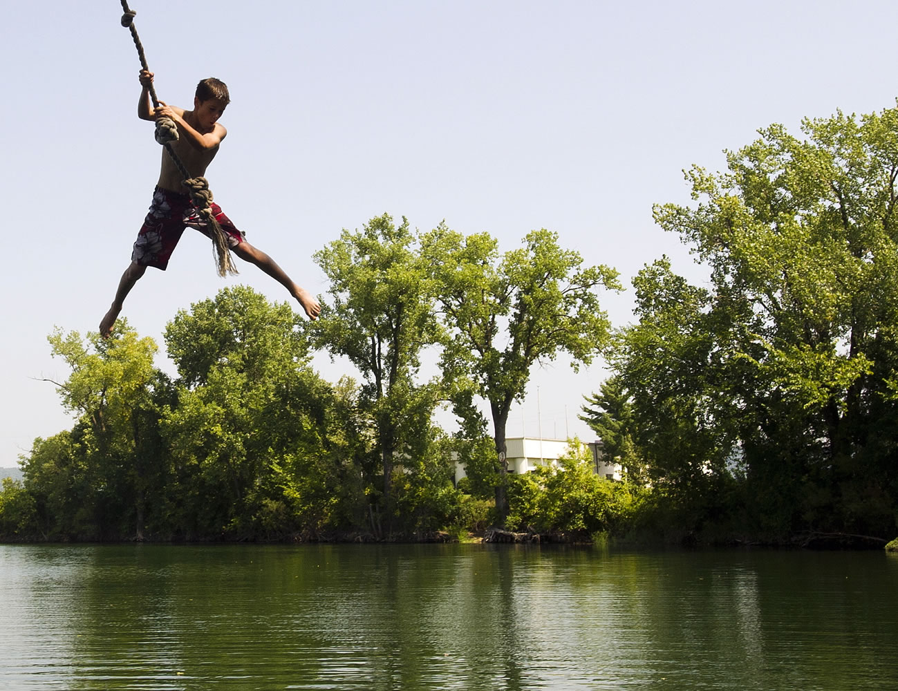 Reece Riebel, 13, of Lewiston, Minn., swings on a rope swing over Airport Lake while swimming Monday in Winona, Minn.