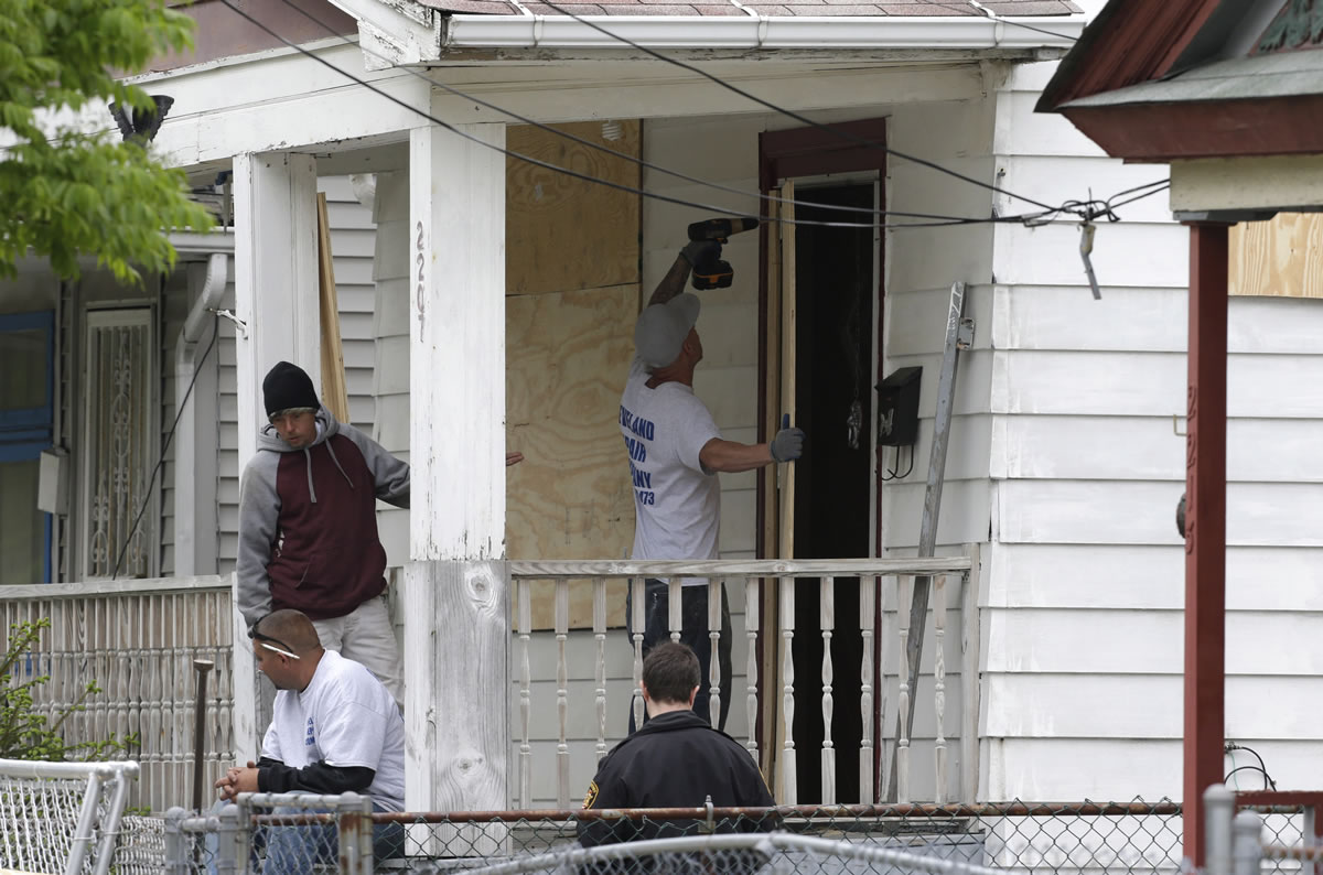 Workers on Saturday board up the house where three women were held in Cleveland.