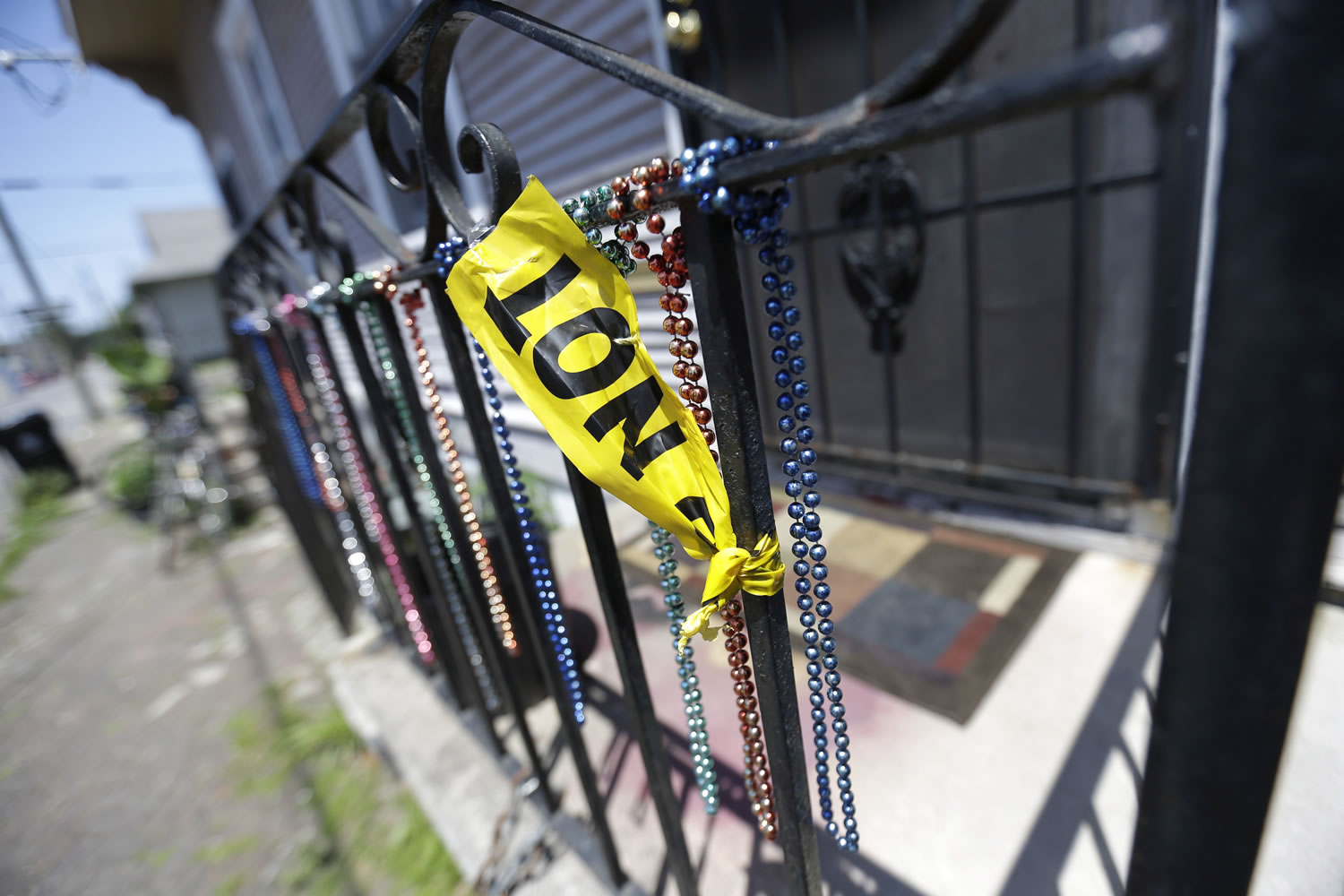 Crime scene tape hangs from a porch, along with Mardi Gras beads, across the street from Sunday's shooting during a second-line parade on Mothers Day in New Orleans.