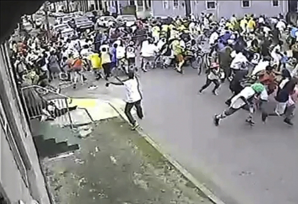 In this image taken from video and provided Monday, May 13, 2013, by the New Orleans Police Department, a possible shooting suspect in a white shirt, bottom center, shoots into a crowd of people, Sunday in New Orleans. Police believe more than one gun was fired in the Mother's Day gunfire that wounded 19 people during a New Orleans neighborhood parade.