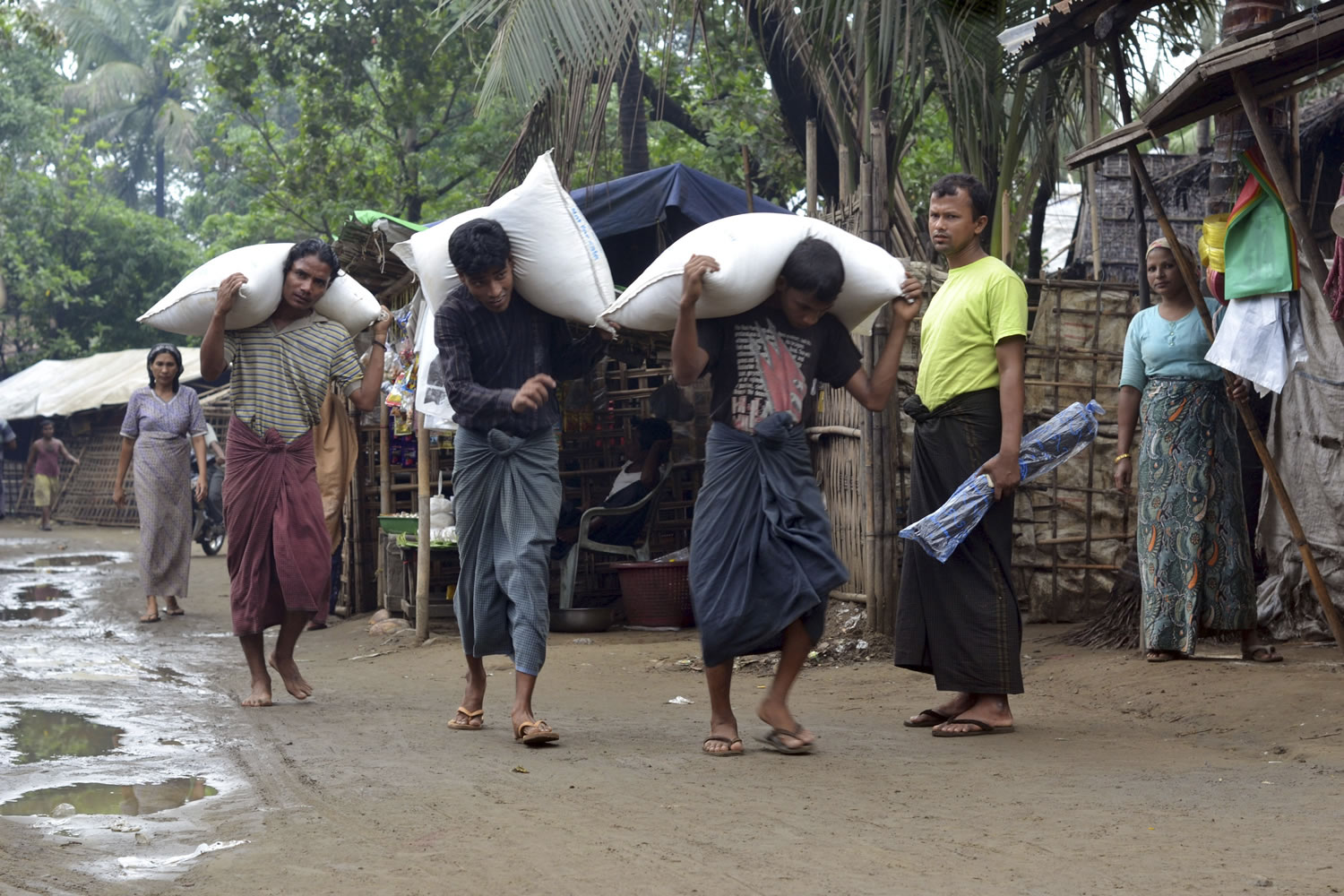Men carry rice sacks as others look on at a refugee camp in Sittwe, western Myanmar, on Wednesday.