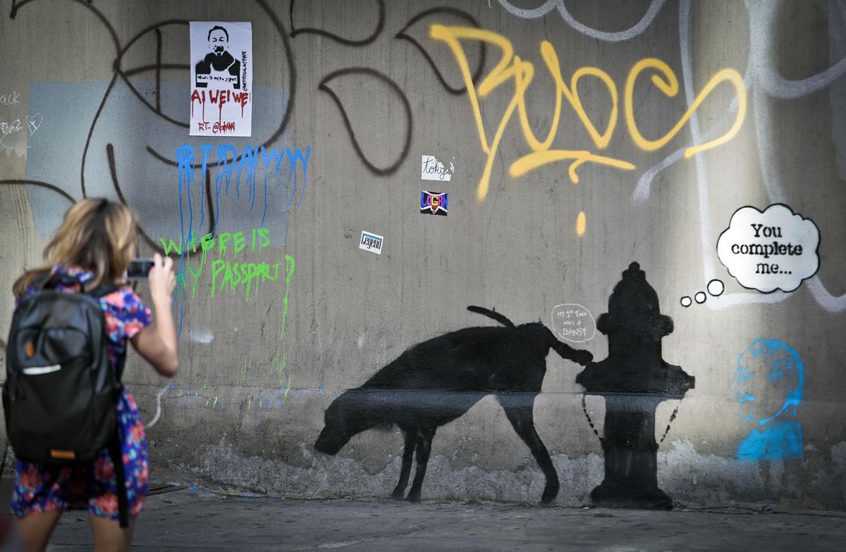 Graffiti by the secretive British artist Banksy, featuring a dog and a fire hydrant, draws attention on 24th Street, near Sixth Avenue in New York.
