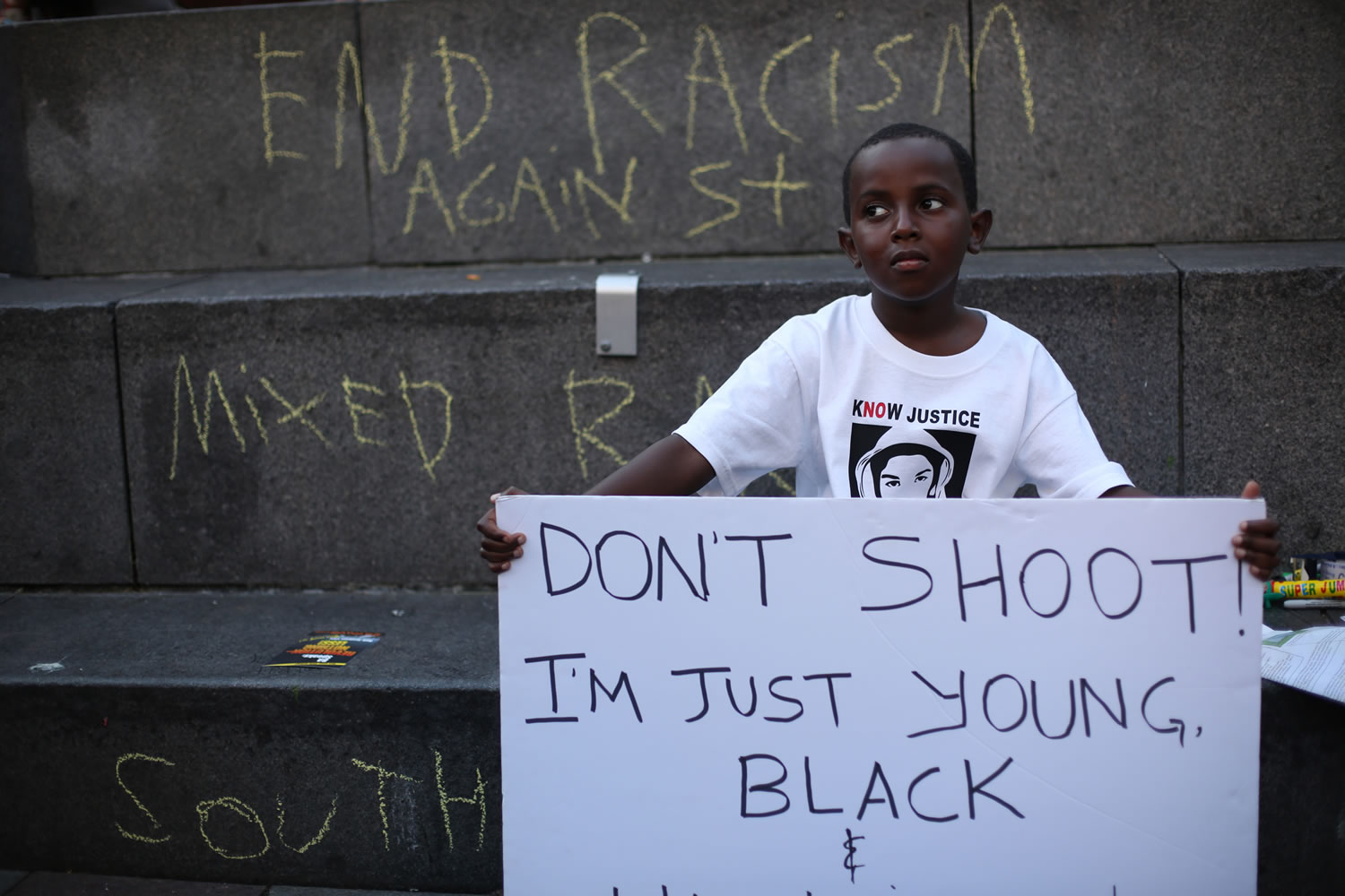 Abdul Kebbeh, 6, holds a sign at Westlake Park on Sunday in downtown Seattle.