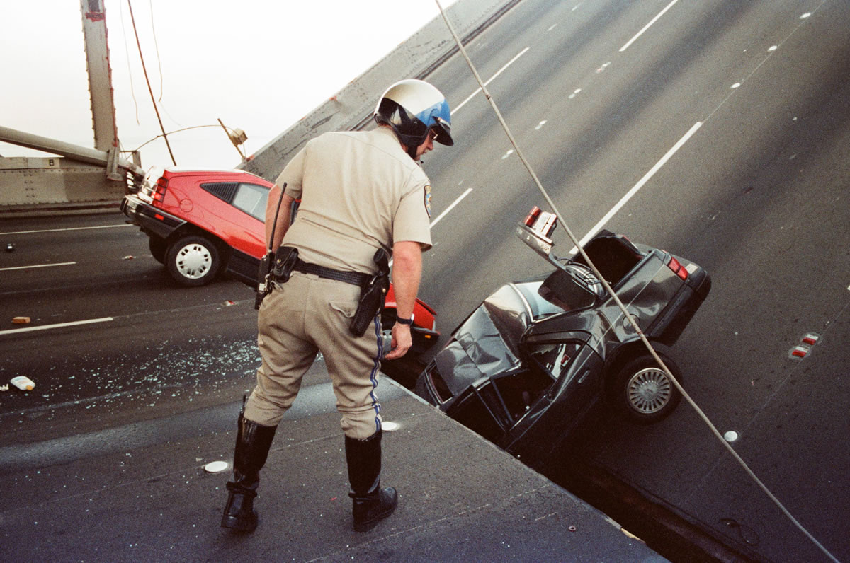 Files/Associated Press
An officer checks damage to cars that fell when the upper deck of the Bay Bridge collapsed on Oct. 17, 1989, after the Loma Prieta earthquake in San Francisco.