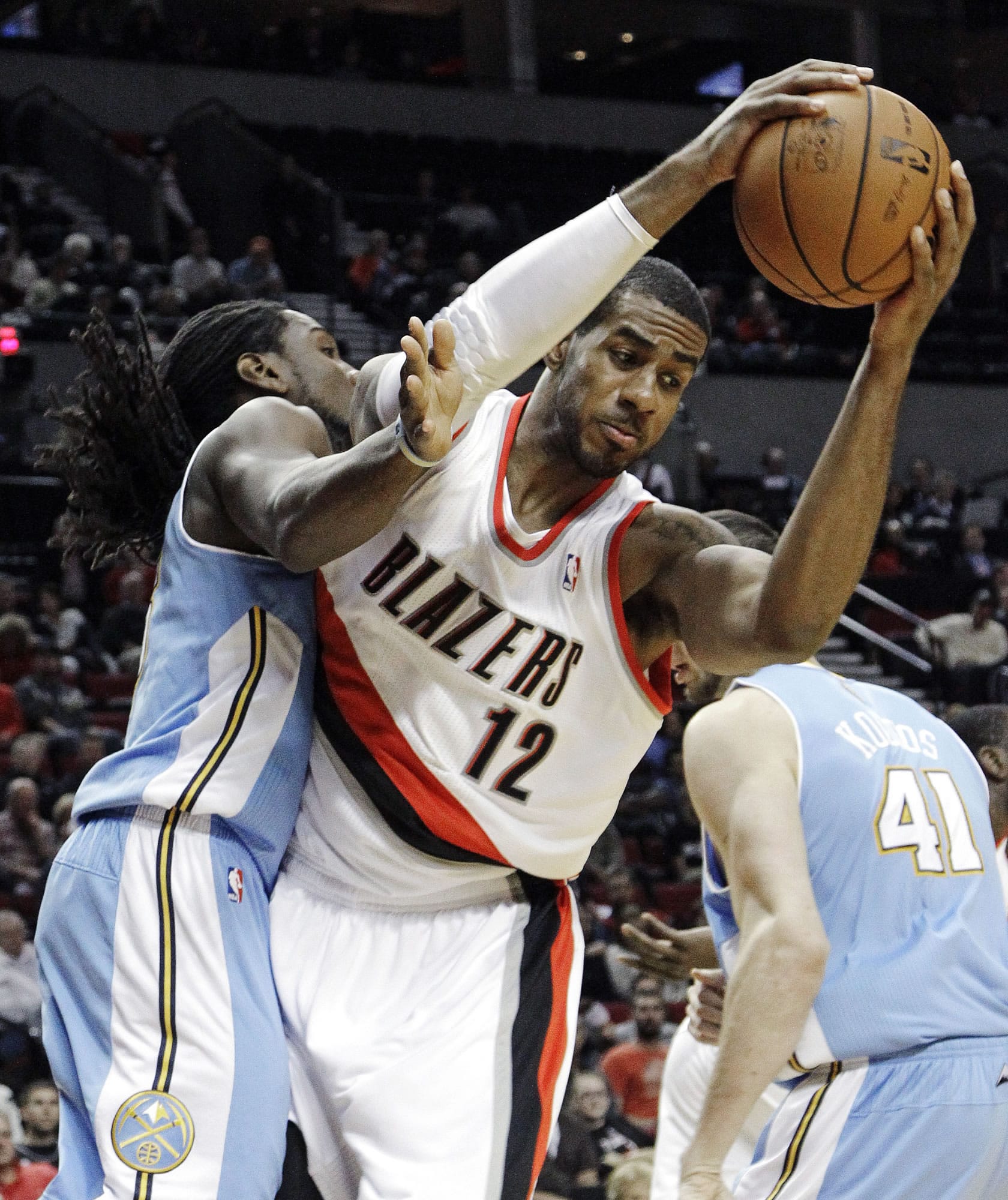Portland Trail Blazers forward LaMarcus Aldridge (12) pulls in a rebound against Denver Nuggets forward Kenneth Faried, left, and center Kosta Koufos (41), of Russia, during the first half of their preseason NBA basketball game Wednesday, Oct.