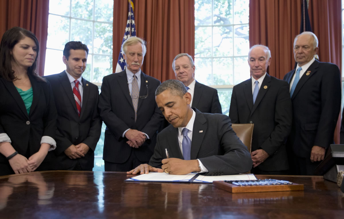President Barack Obama signs the bipartisan bill to cut student loan interest rates Friday in the Oval Office of the White House in Washington.