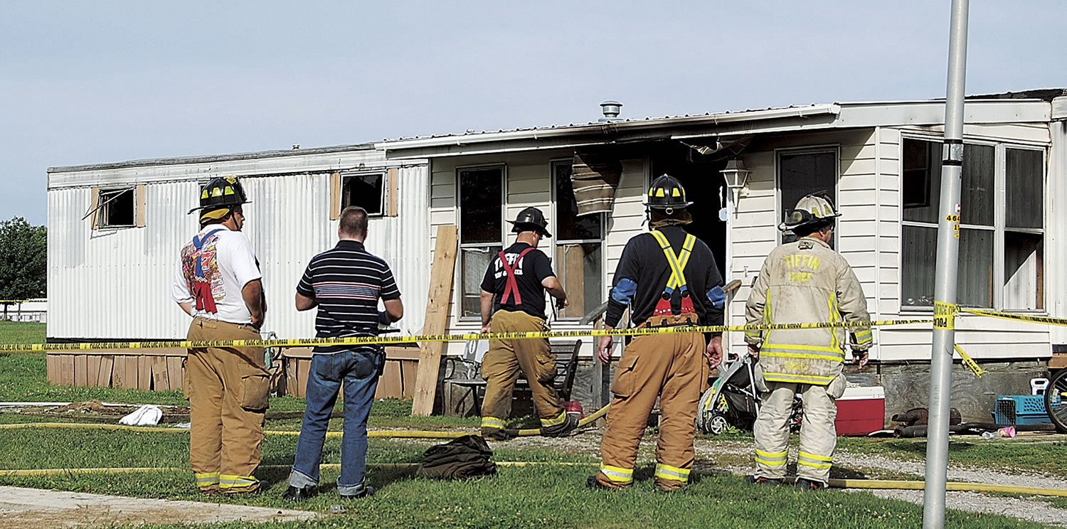 Fire officials stand outside a mobile home that caught fire and killed a man and five children in Tiffin, Ohio, on Sunday. Fire crews pulled the man and the children from the home, and all six were taken to Tiffin Mercy Hospital, where they were pronounced dead. The fire was reported shortly before 8 a.m.