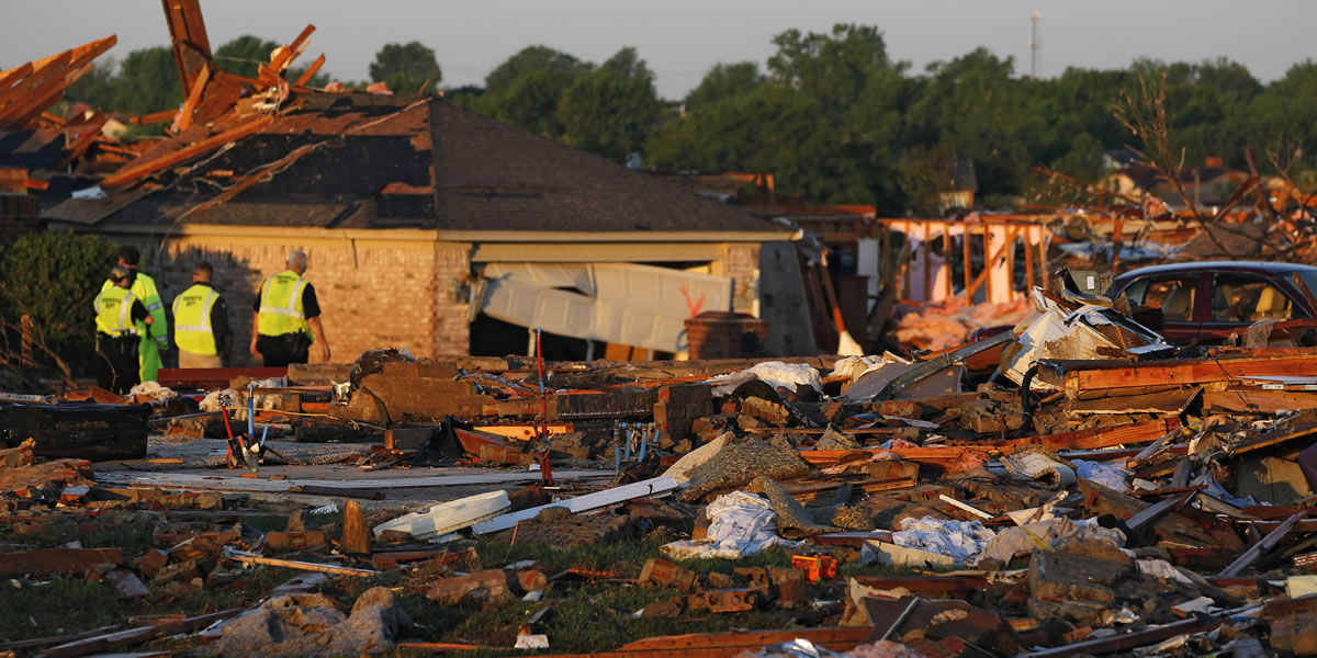 At sunrise, police patrol a partially-destroyed row of houses adjacent to a group of homes completely leveled on Monday when a tornado moved through Moore, Okla., on Wednesday.